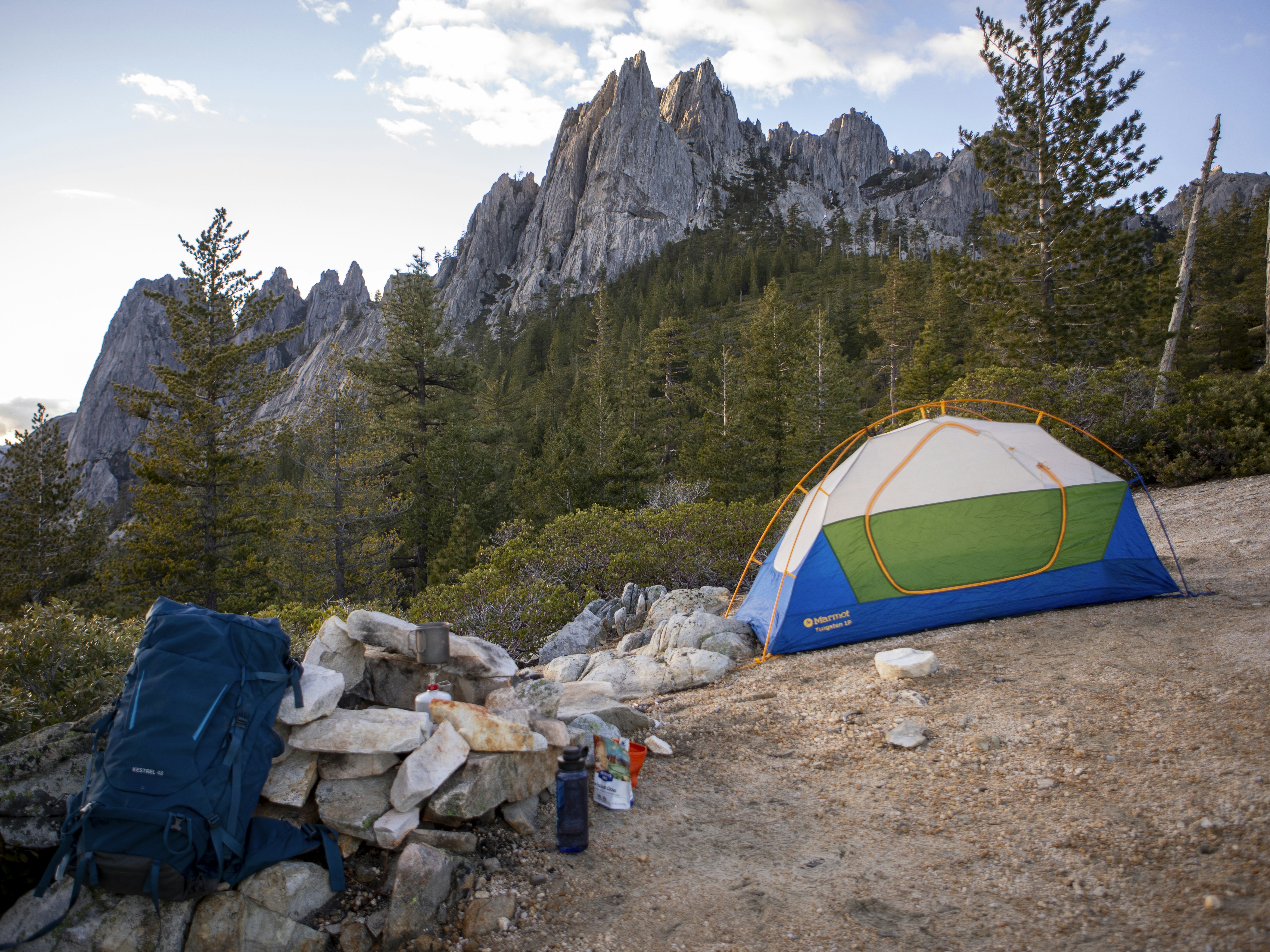 Tent set up at a campsite with rocky mountains behind.