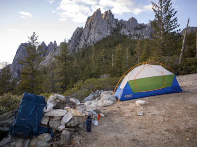 Tent set up at a campsite with rocky mountains behind.