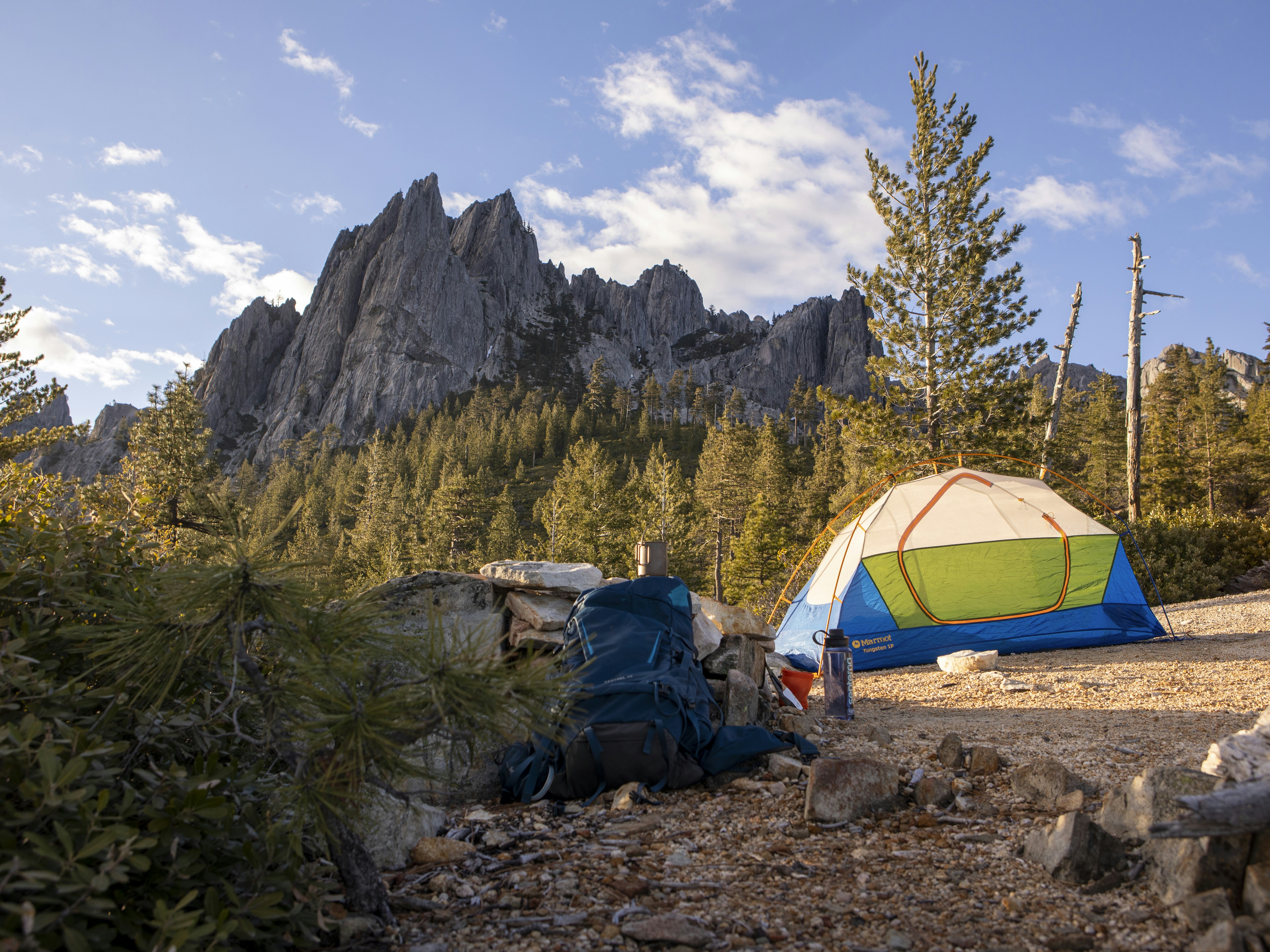 Tent and backpack at a campsite with rocky mountains.