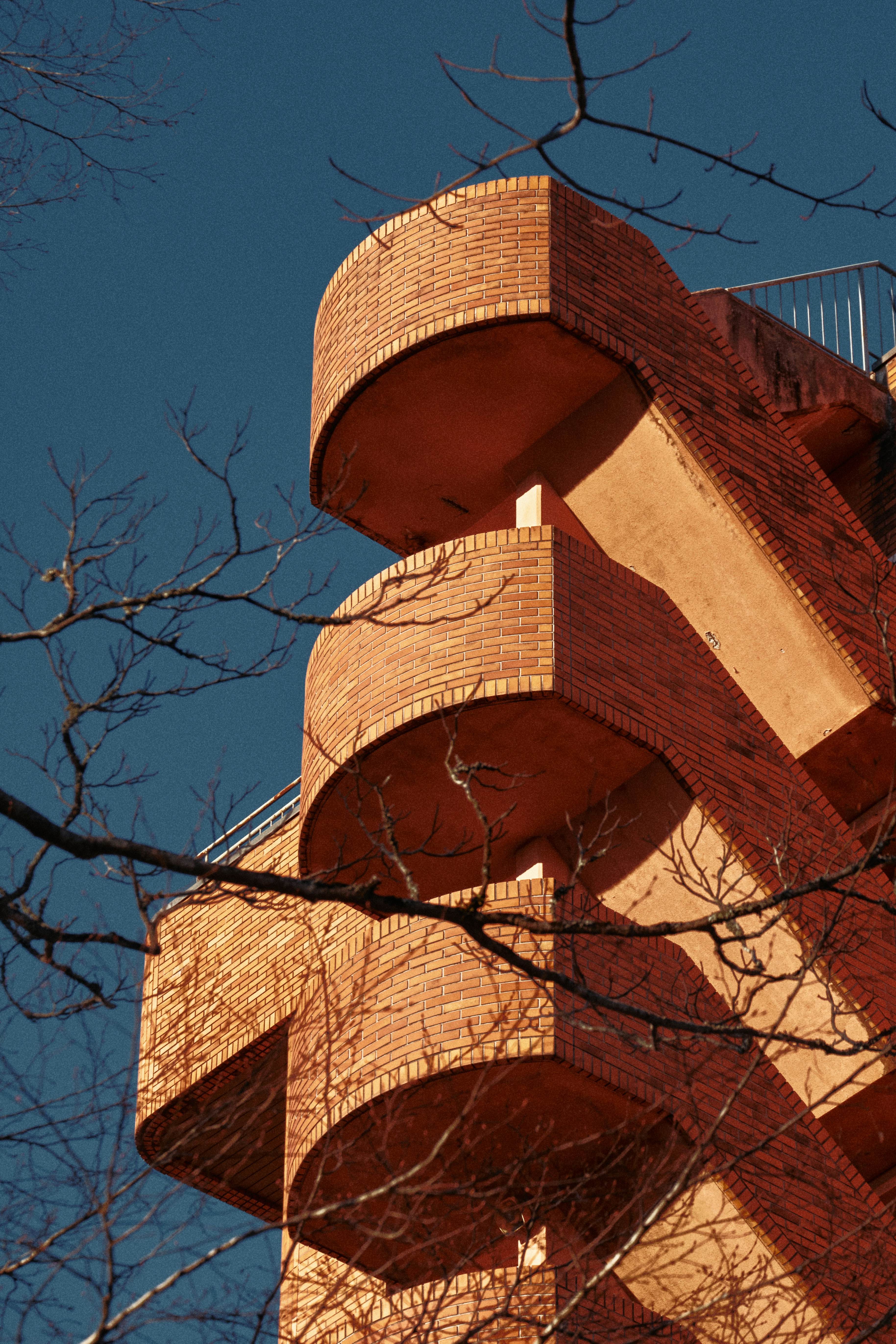 Modern brick building with curved balconies against blue sky