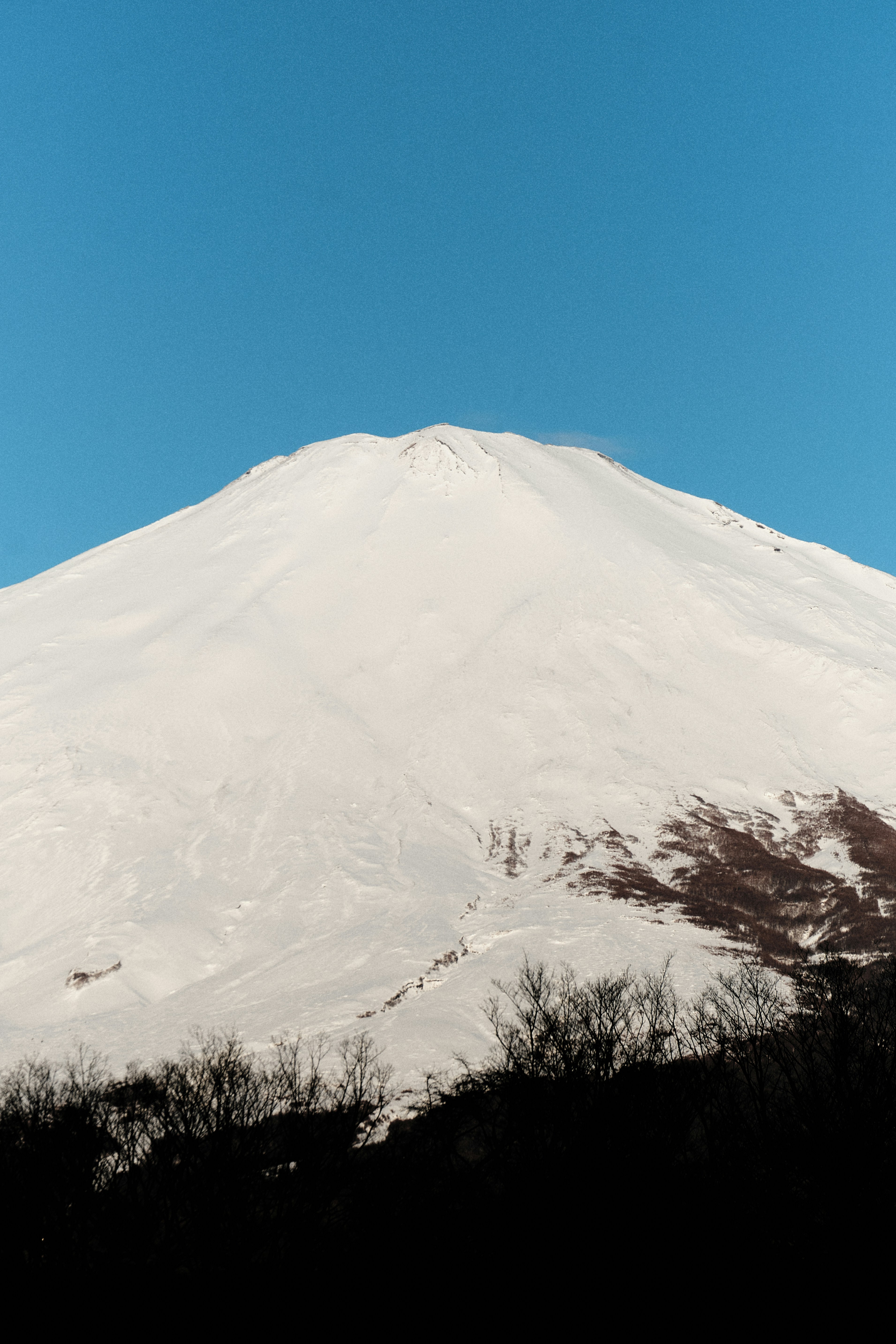 Snow covered mountain peak under a clear blue sky.