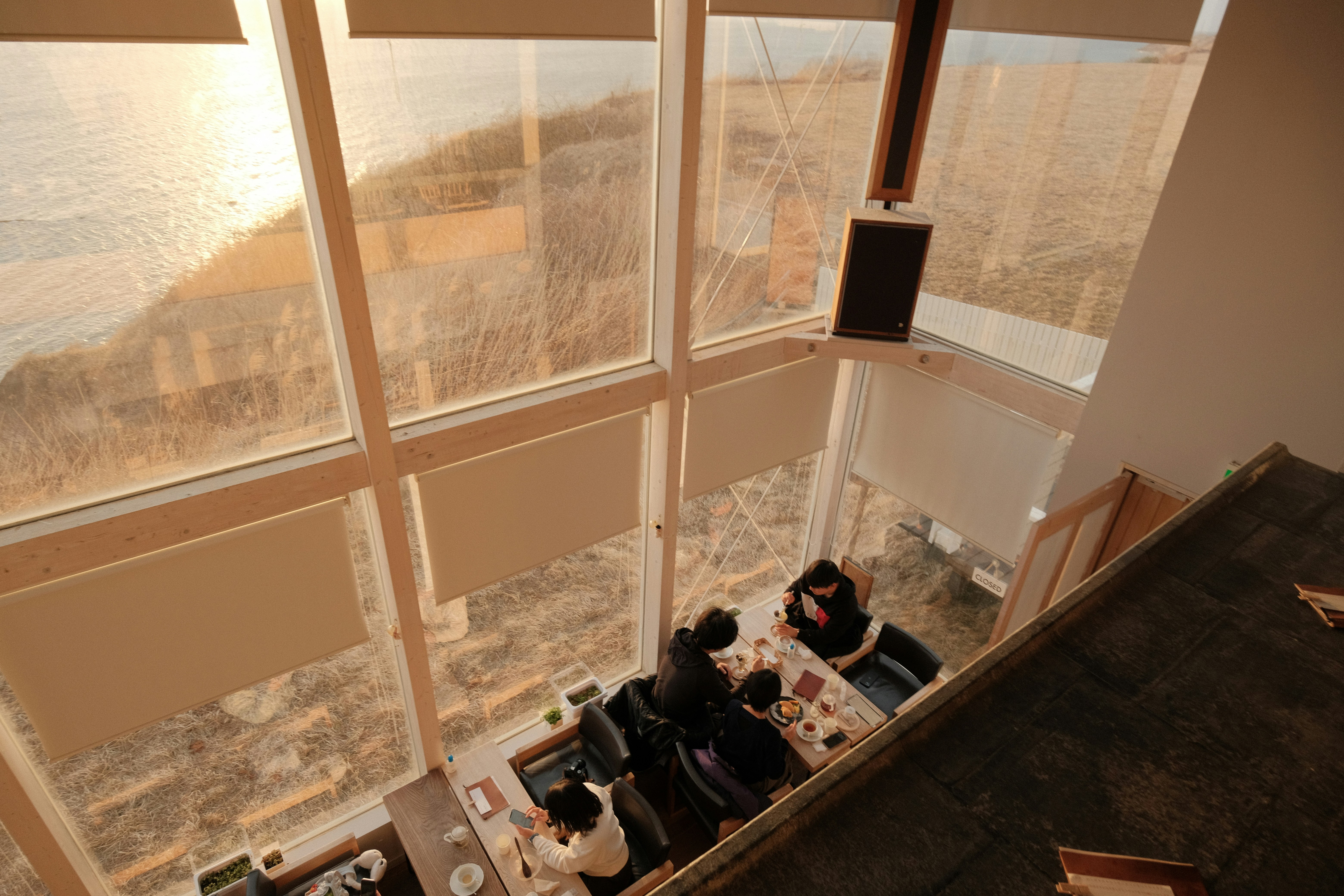 Two people sit at a table by large windows.
