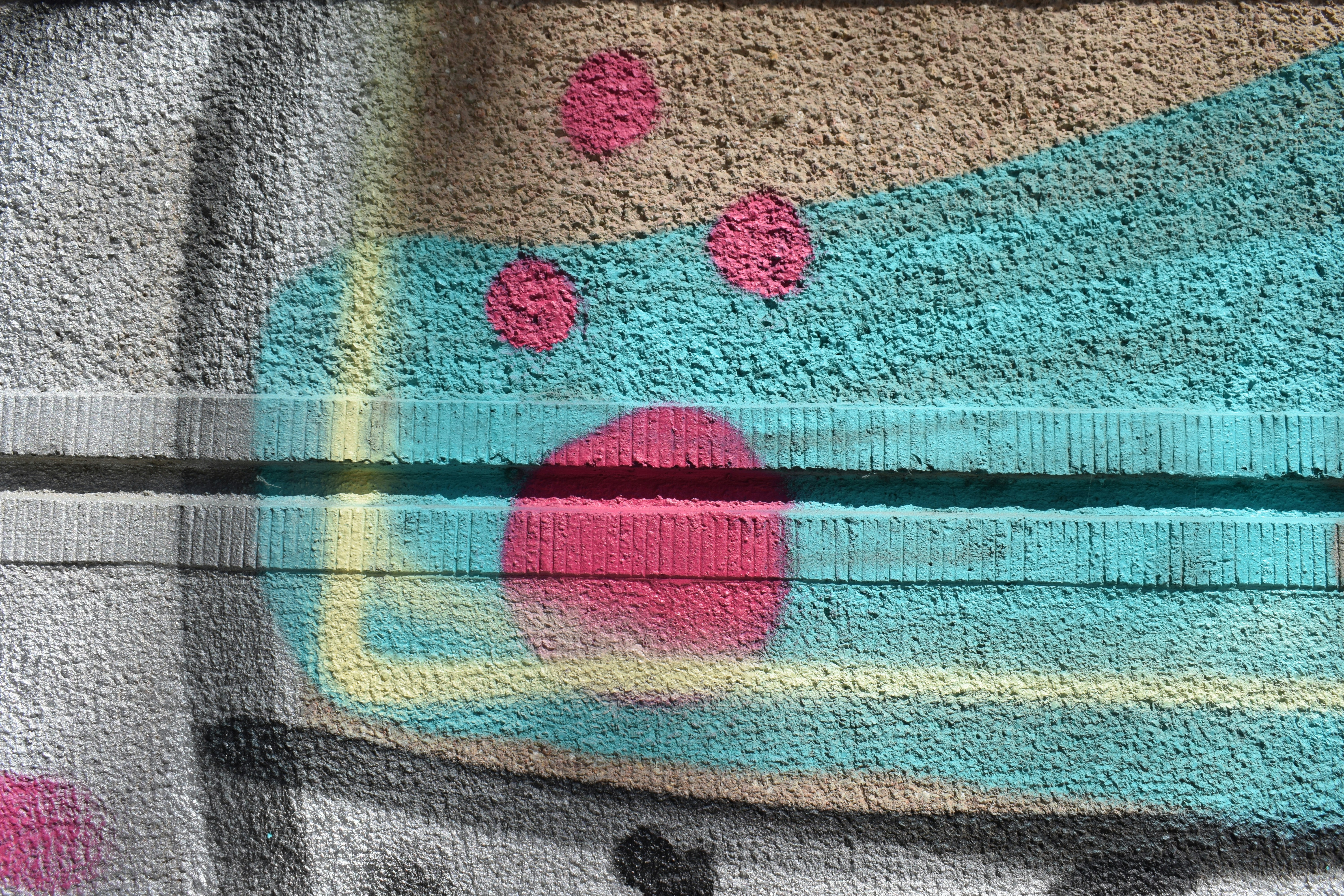 Primer plano de grafitis coloridos con puntos rosas en la pared.