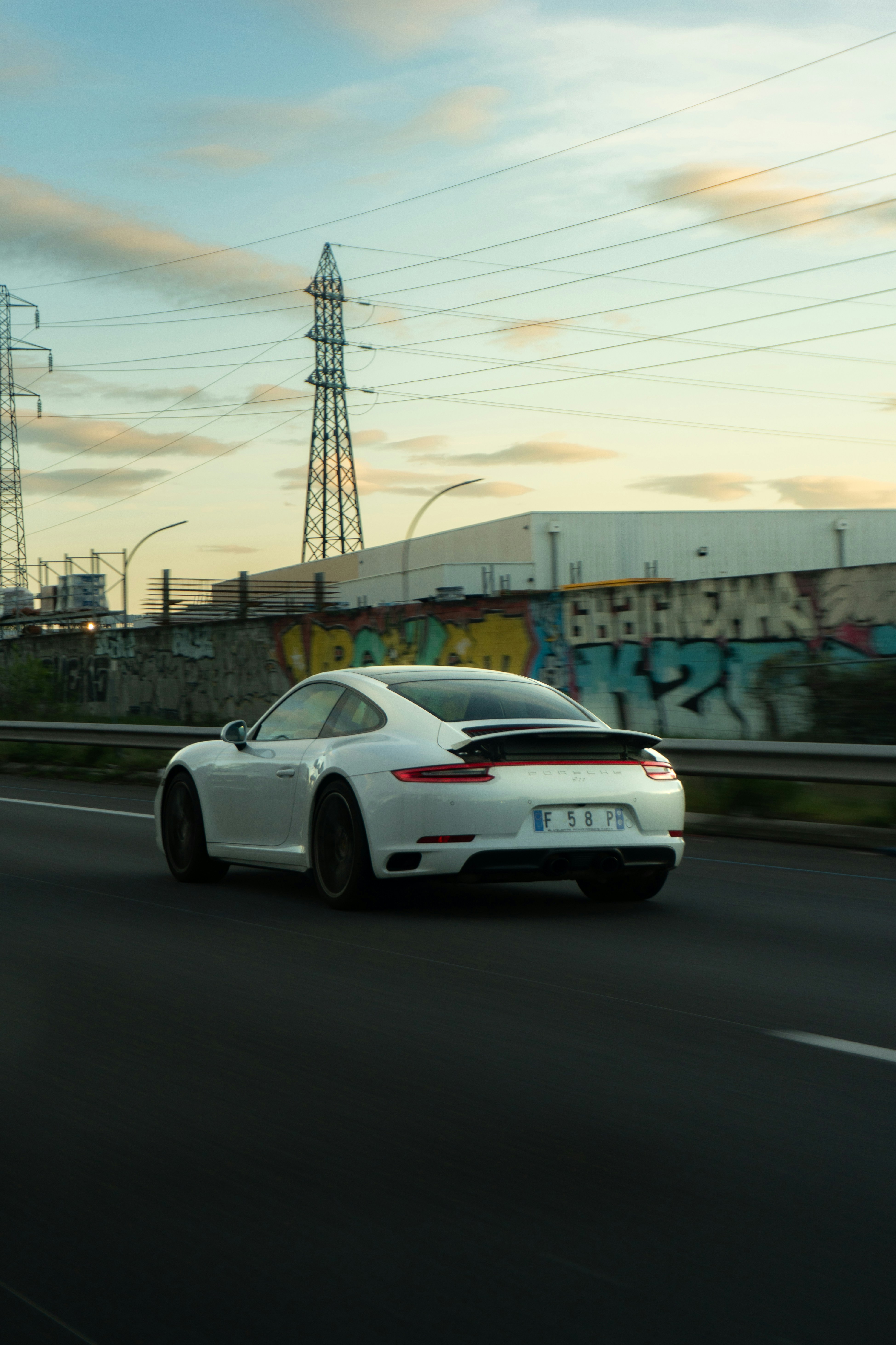 White sports car driving on a highway at dusk.