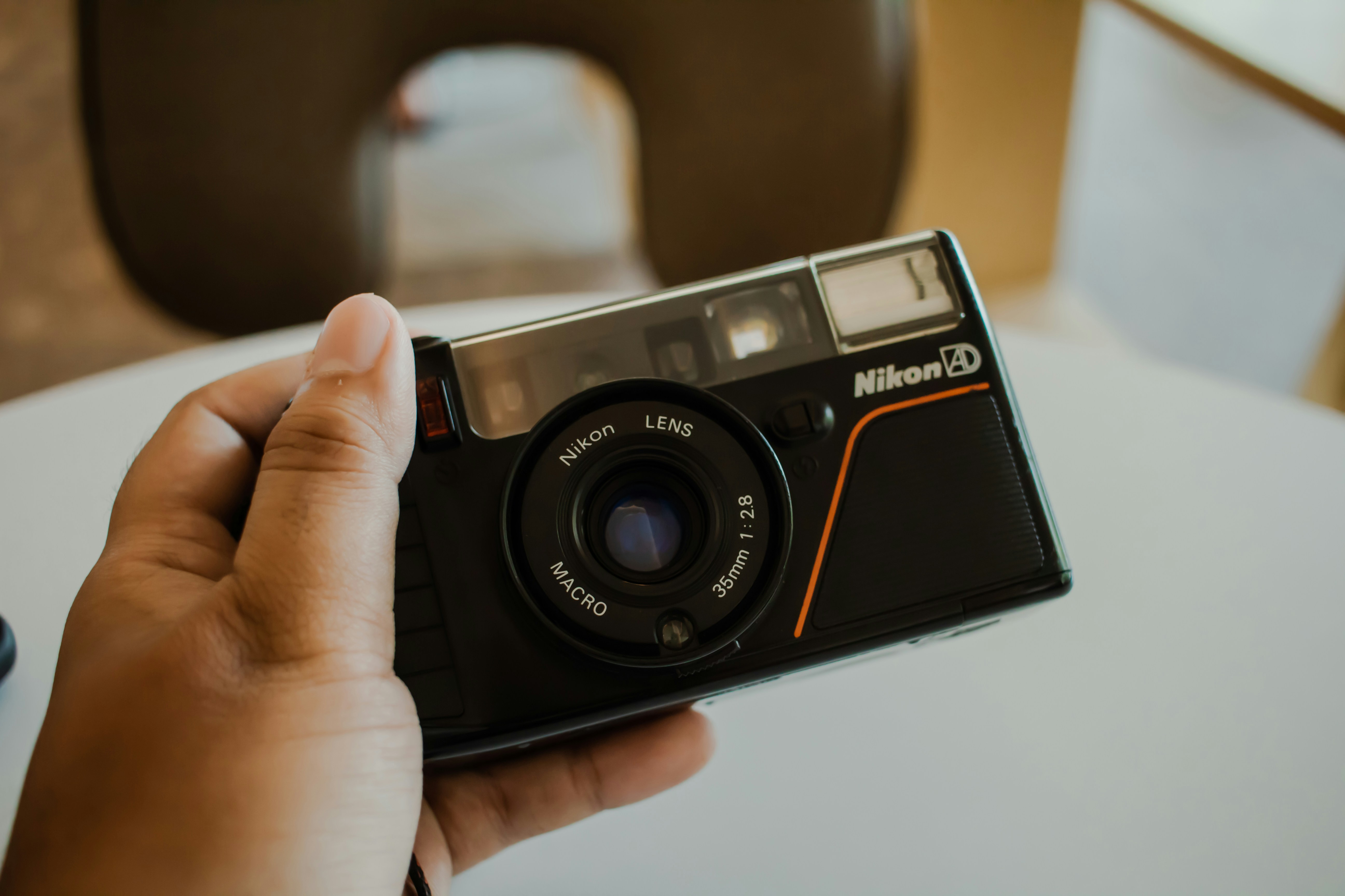 黒いニコンの35mmフィルムカメラを手に持っている。