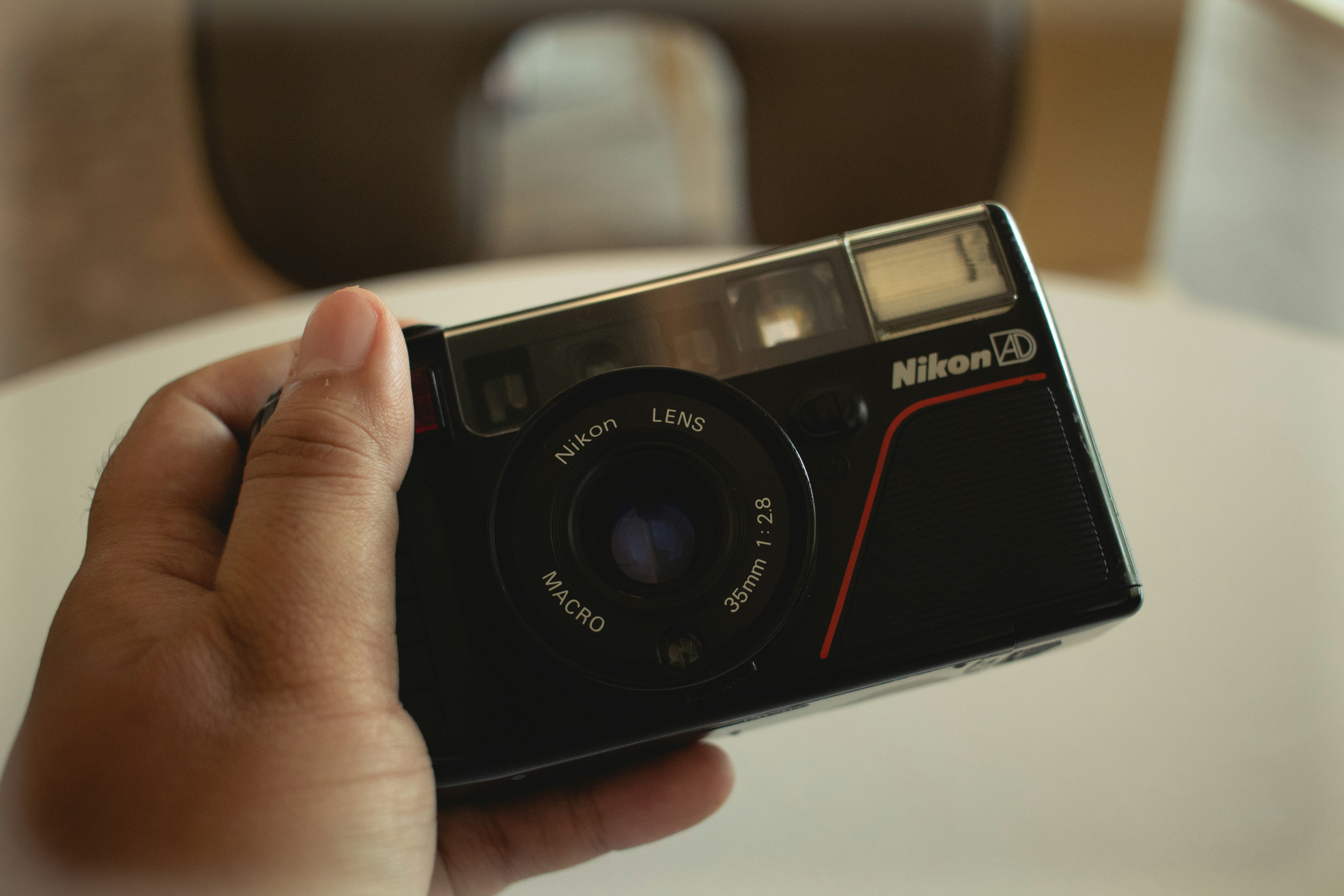 黒いニコンのコンパクトカメラを手に持っている。