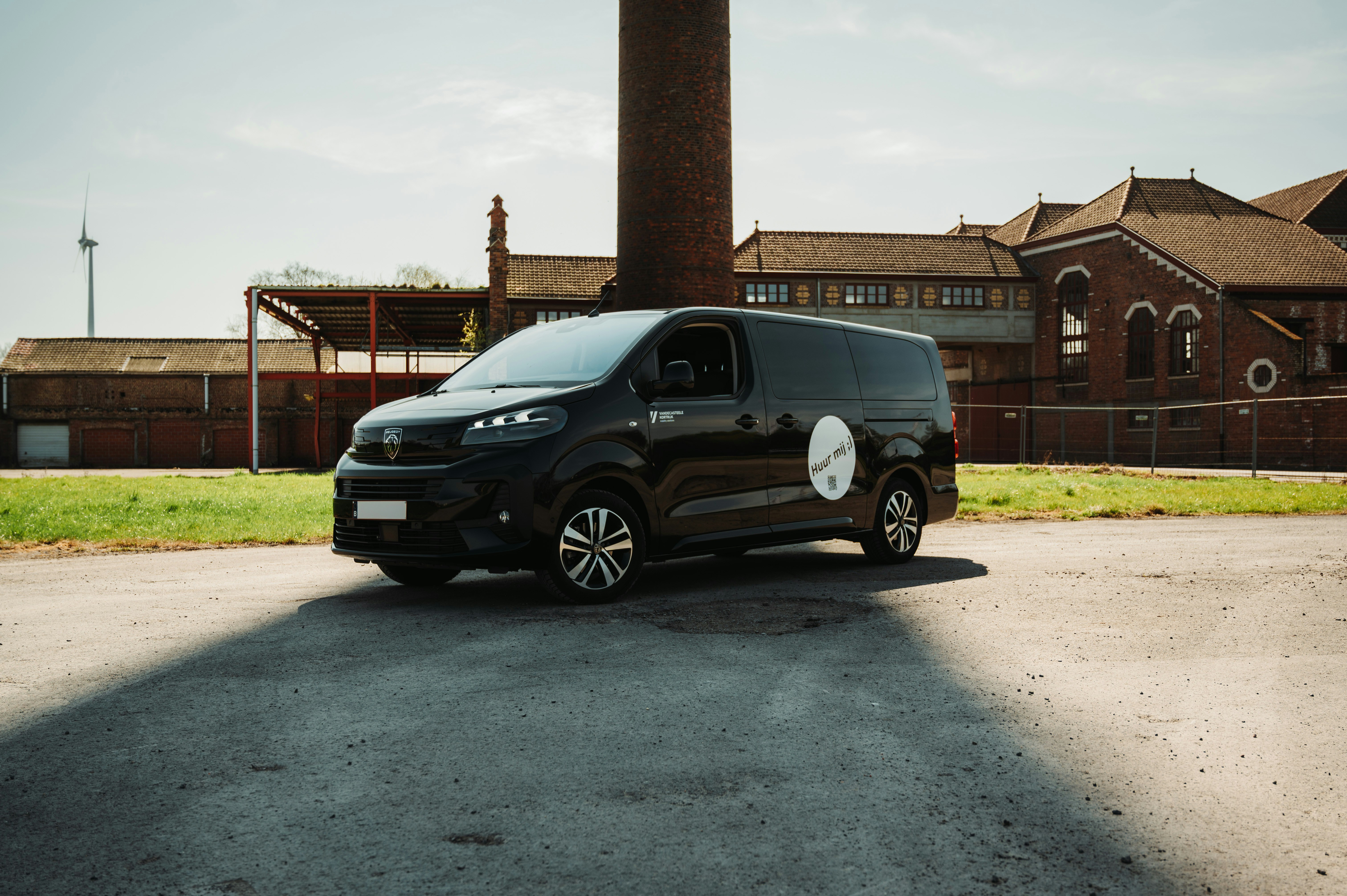 A black van parked in front of an industrial building.