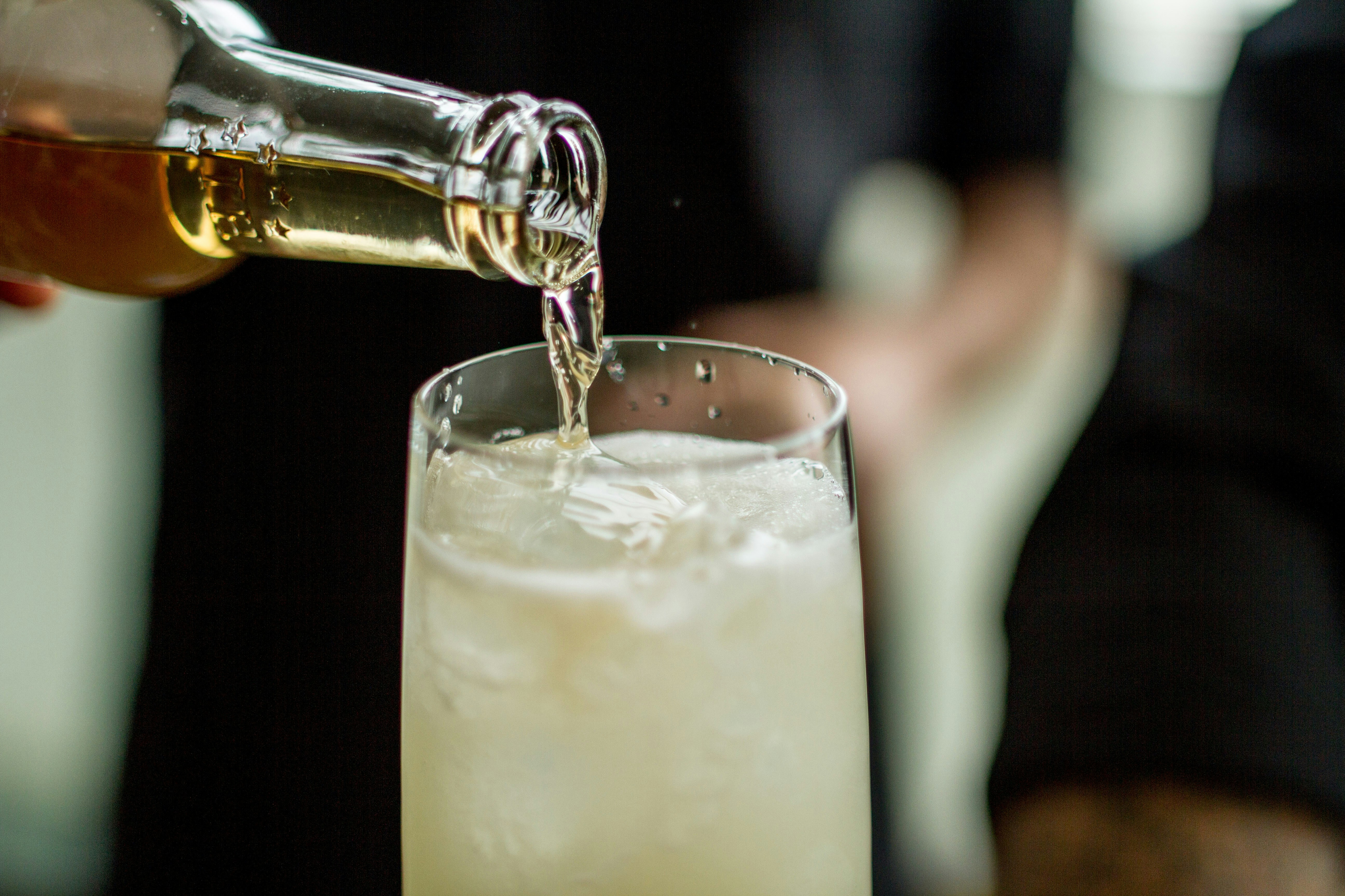 Liquid being poured from bottle into a tall glass