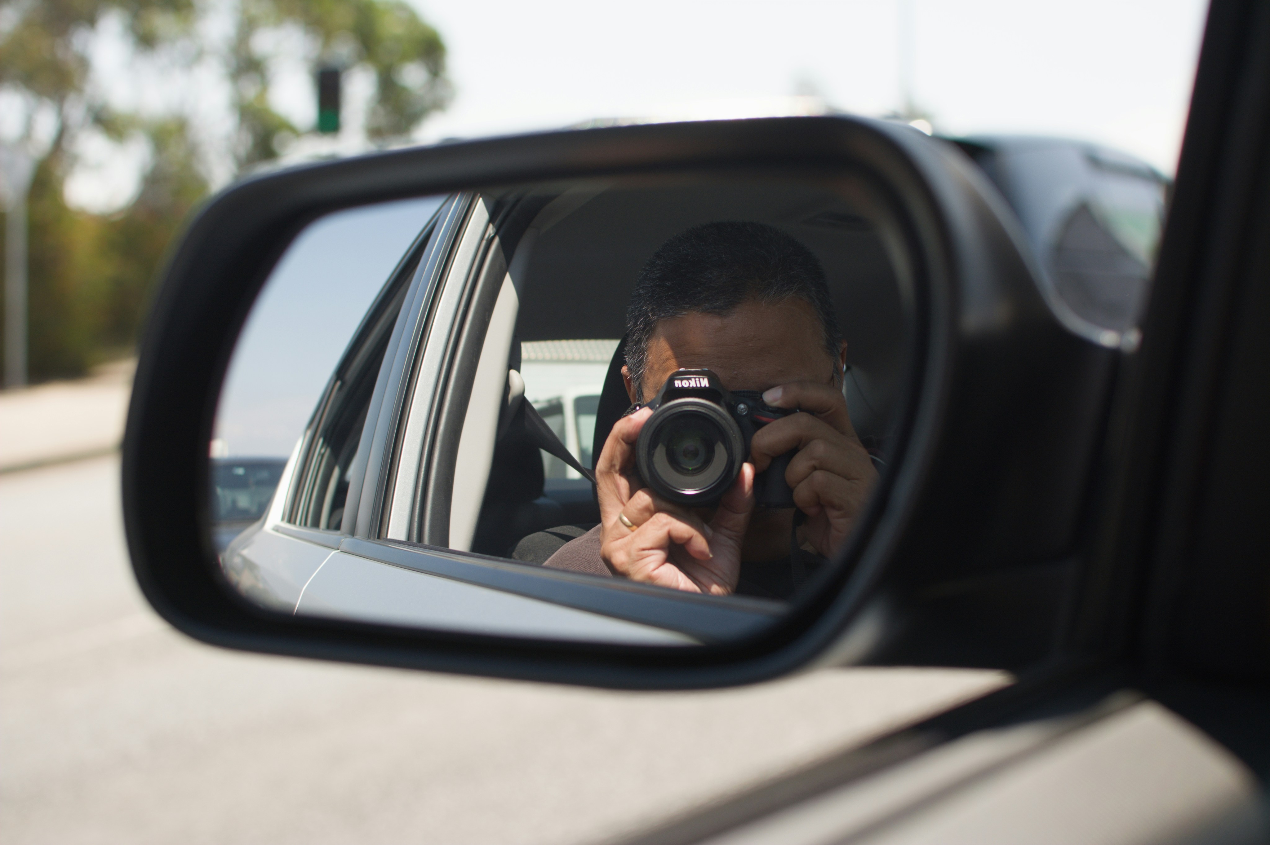Man taking a selfie in car side mirror