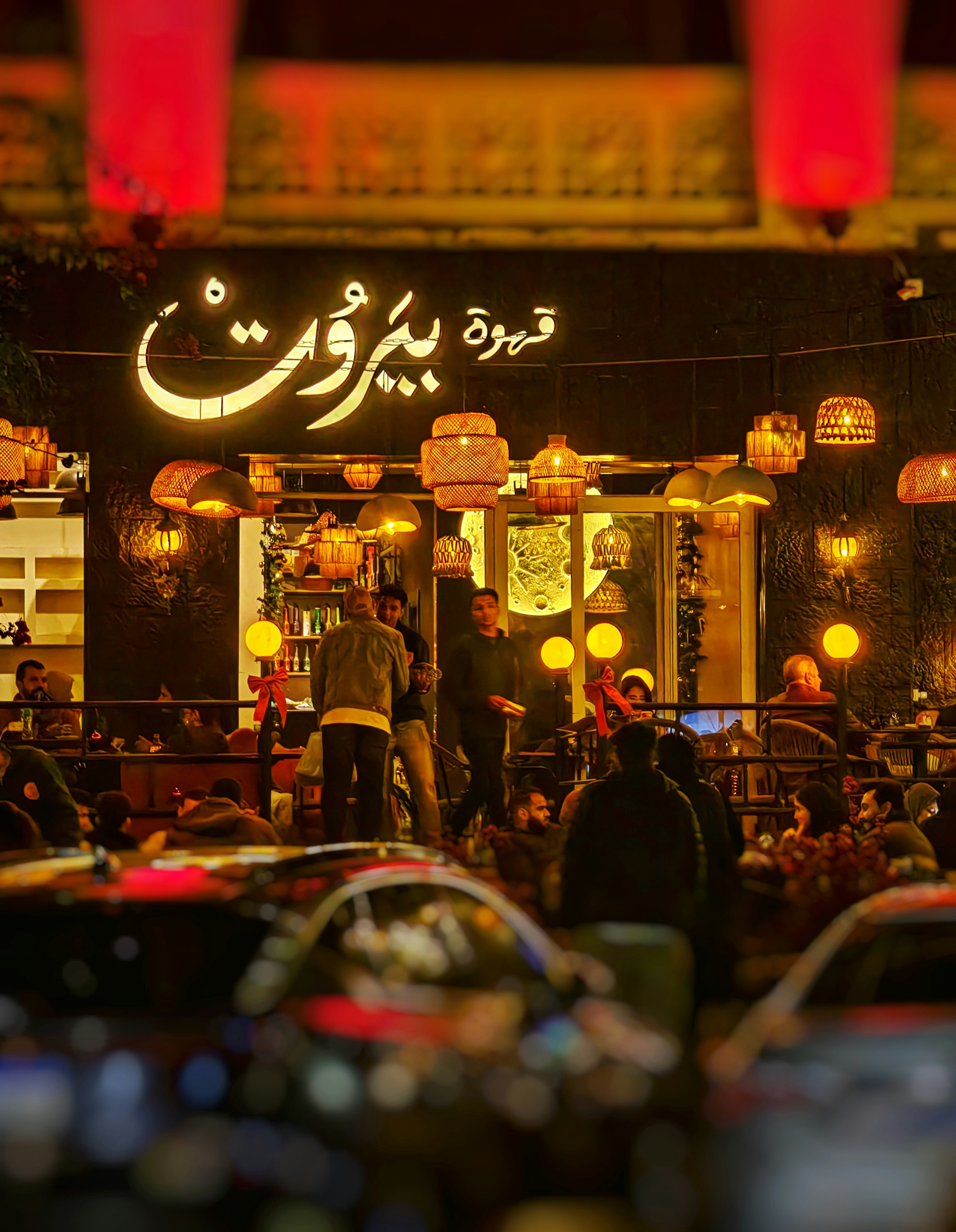 People gather at a warmly lit cafe at night