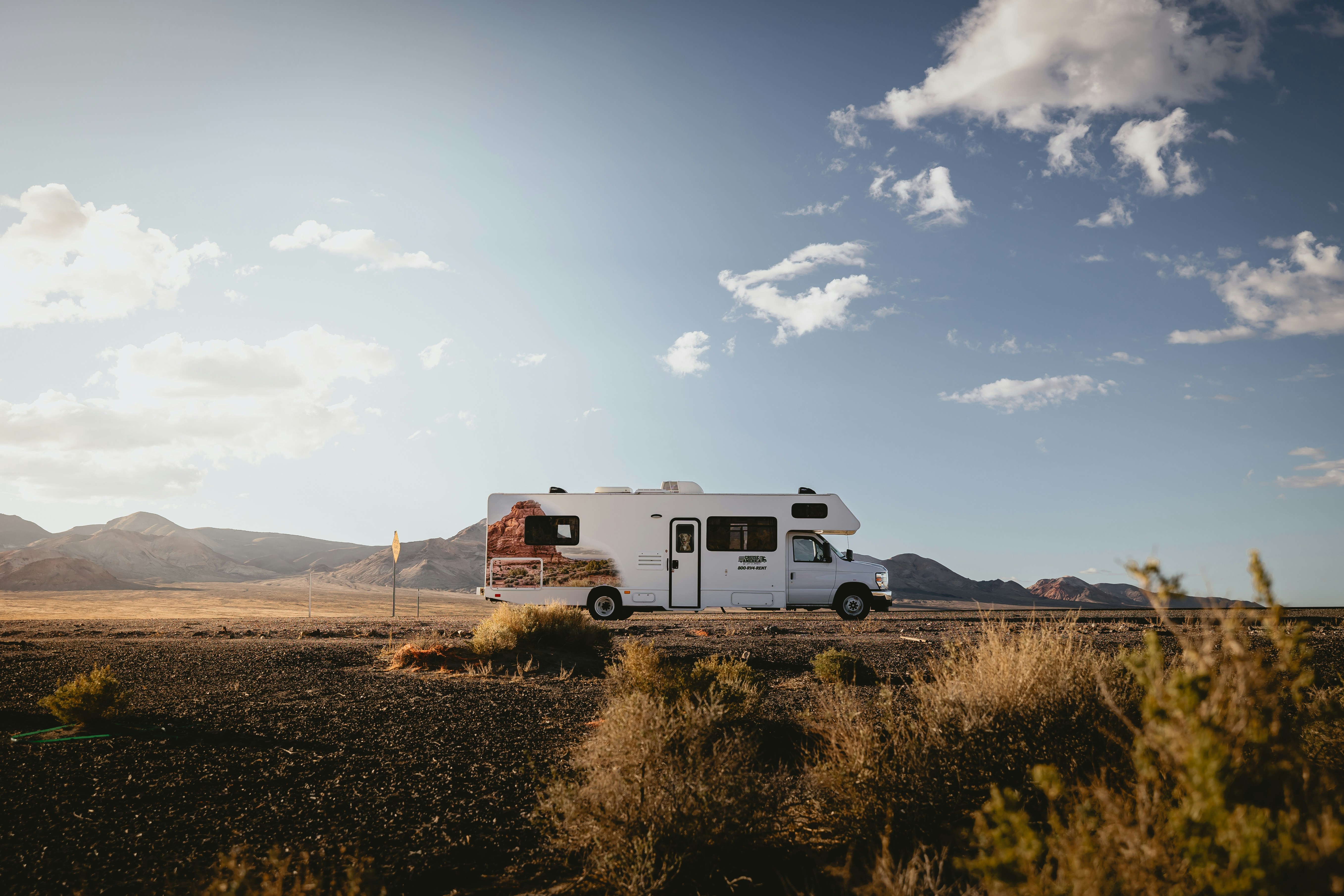 Una autocaravana blanca circula por una carretera del desierto.
