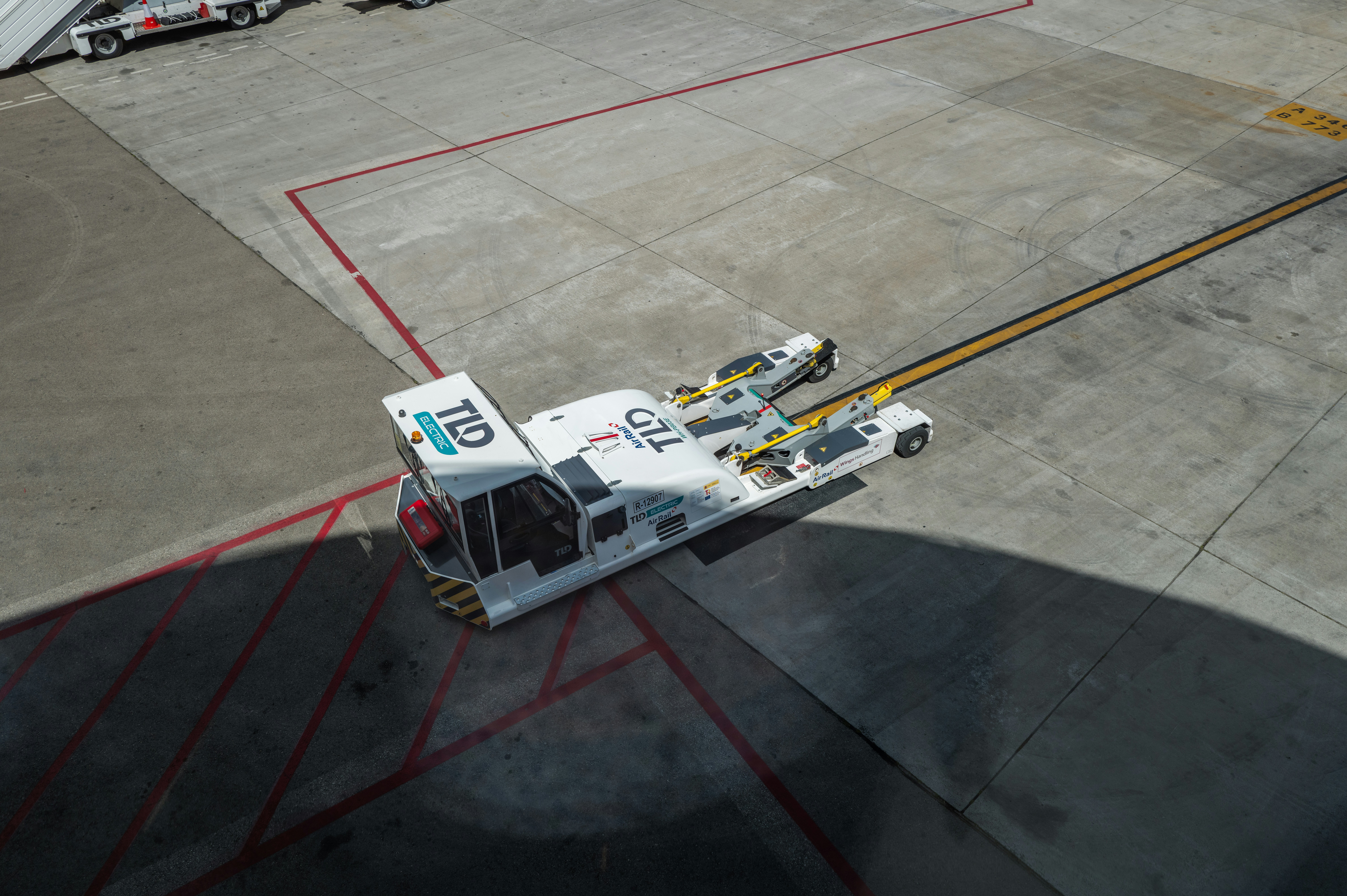 Rimorchiatore bianco di aerei sulla pista aeroportuale con linee gialle