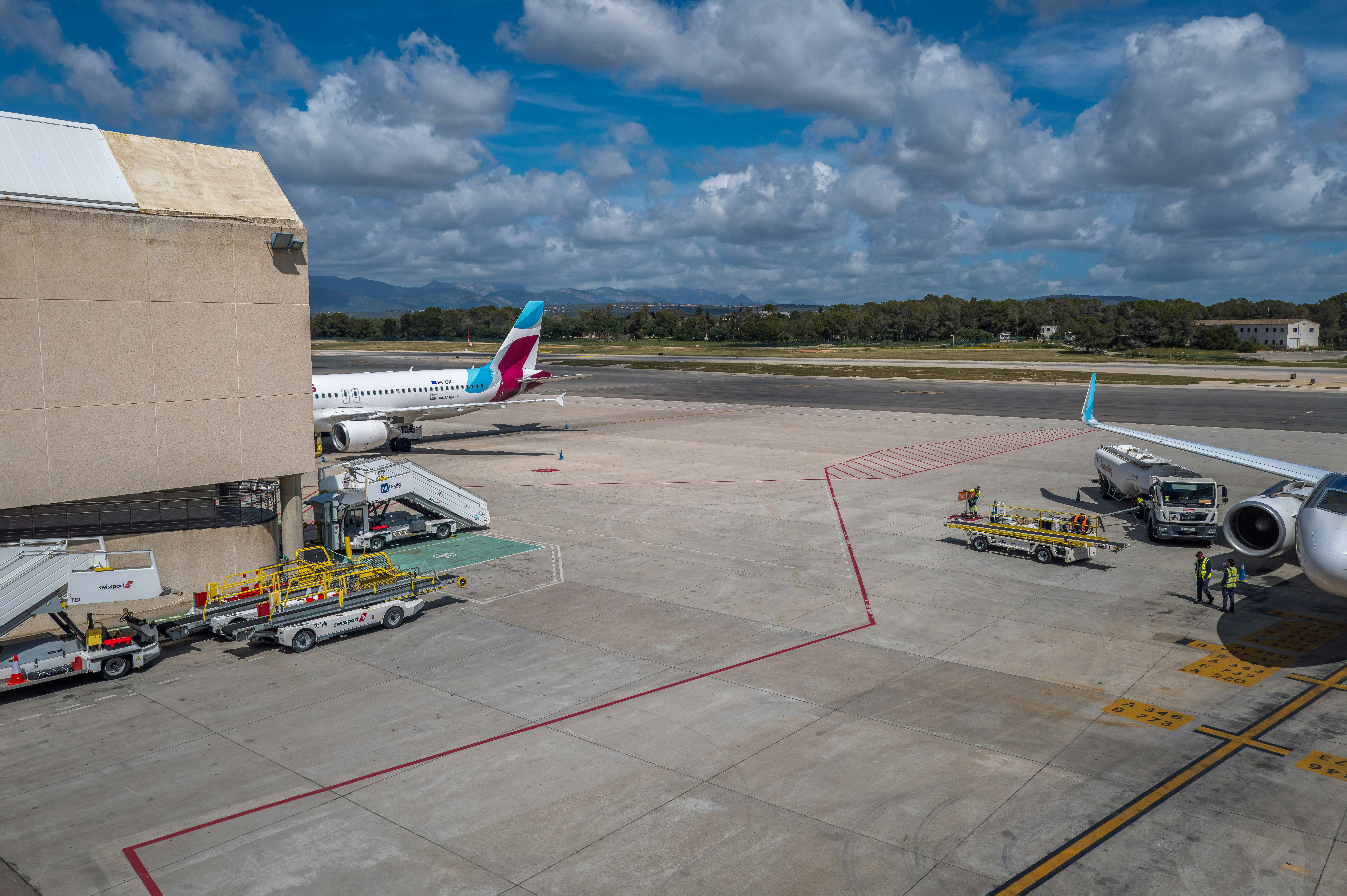 Aerei al gate dell'aeroporto con ponte di volo e personale di terra.