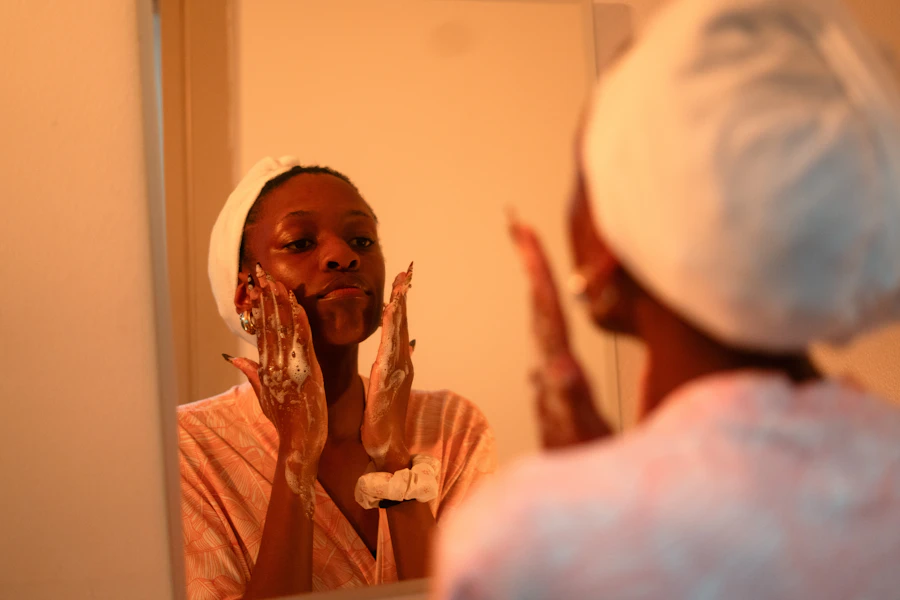 Woman applying facial cleanser in front of mirror