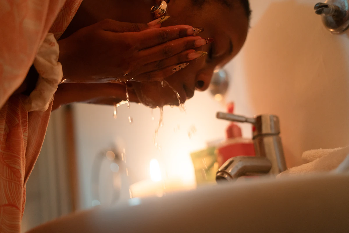 Woman washing her face at a bathroom sink