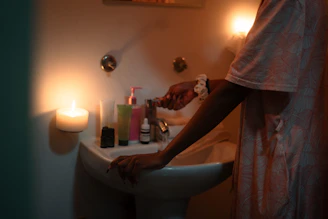 Person washing hands in sink by candlelight