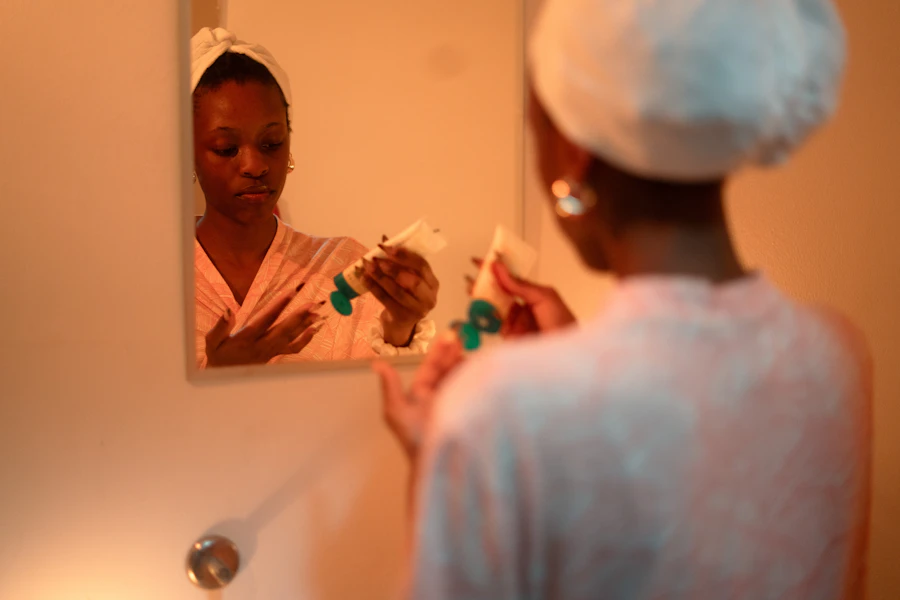 Woman applying cream to her face in mirror