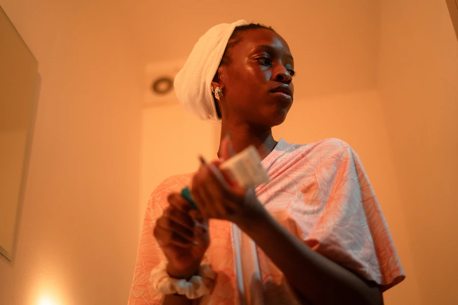 Young woman applies cream to her face