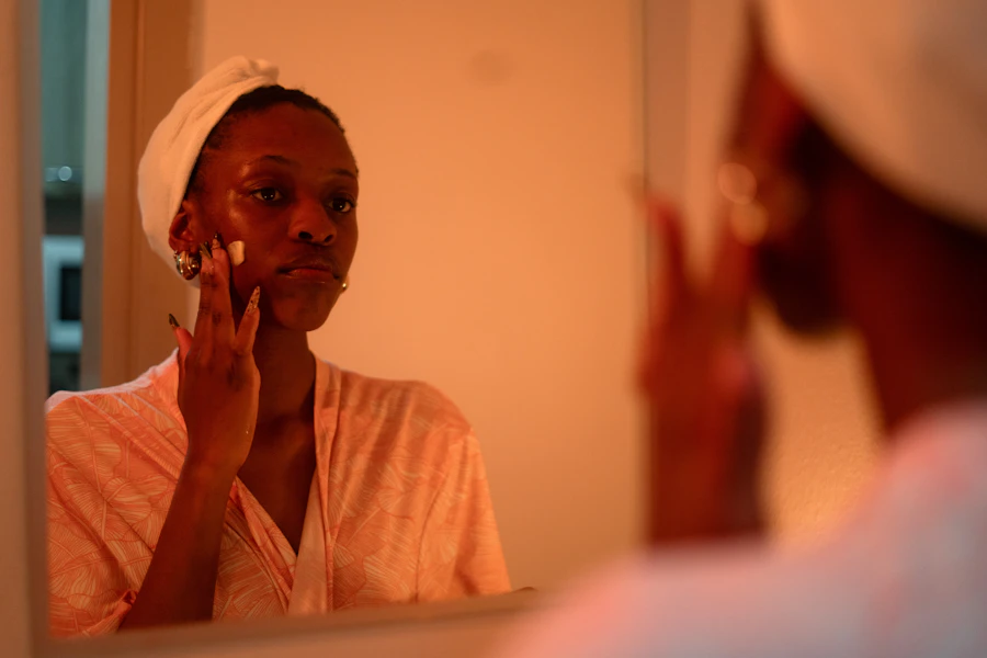 Woman applying face cream in front of a mirror