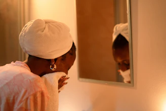 Woman drying her face with a towel in the mirror.
