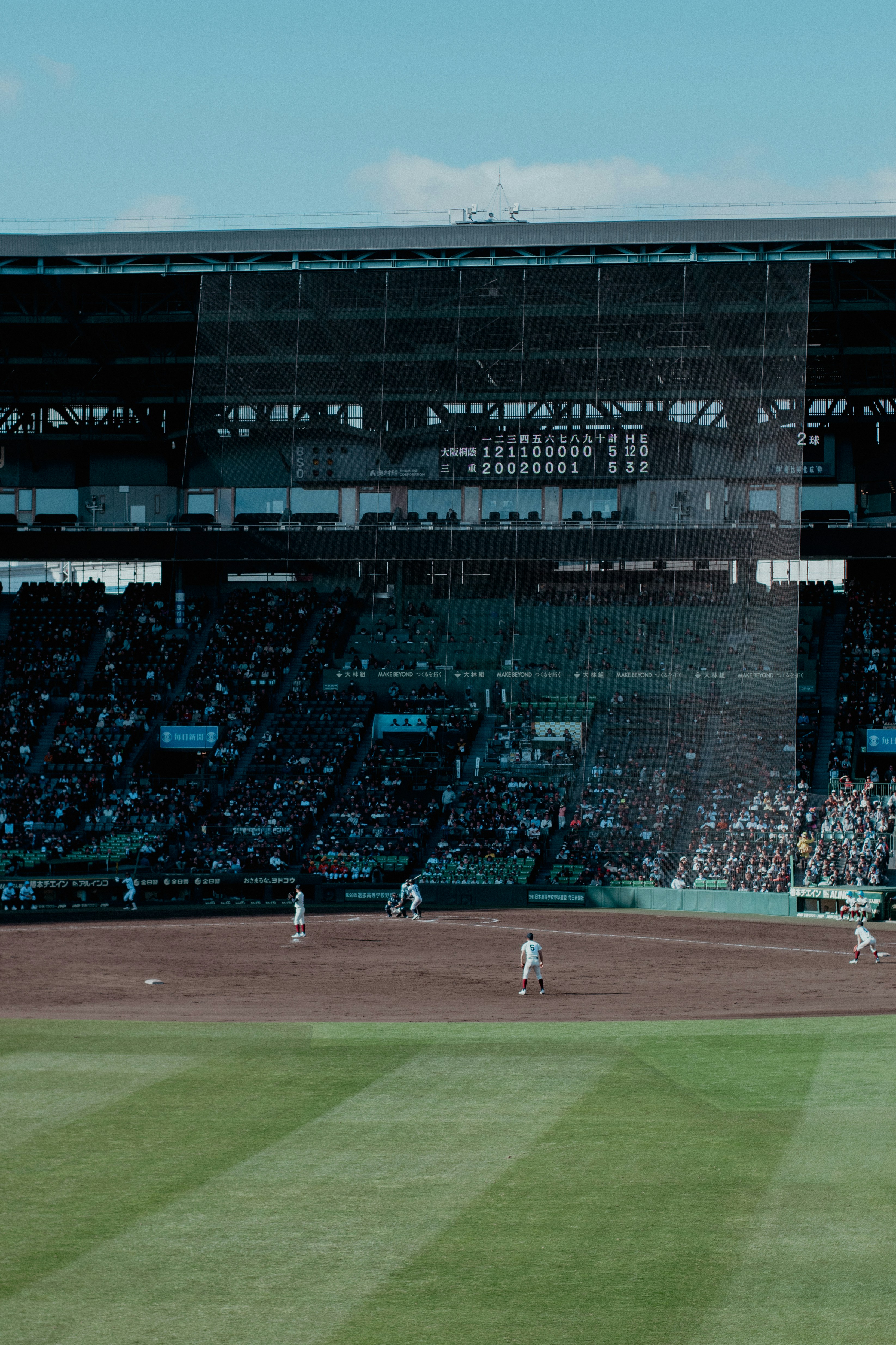 Baseball players on a field with a stadium crowd.