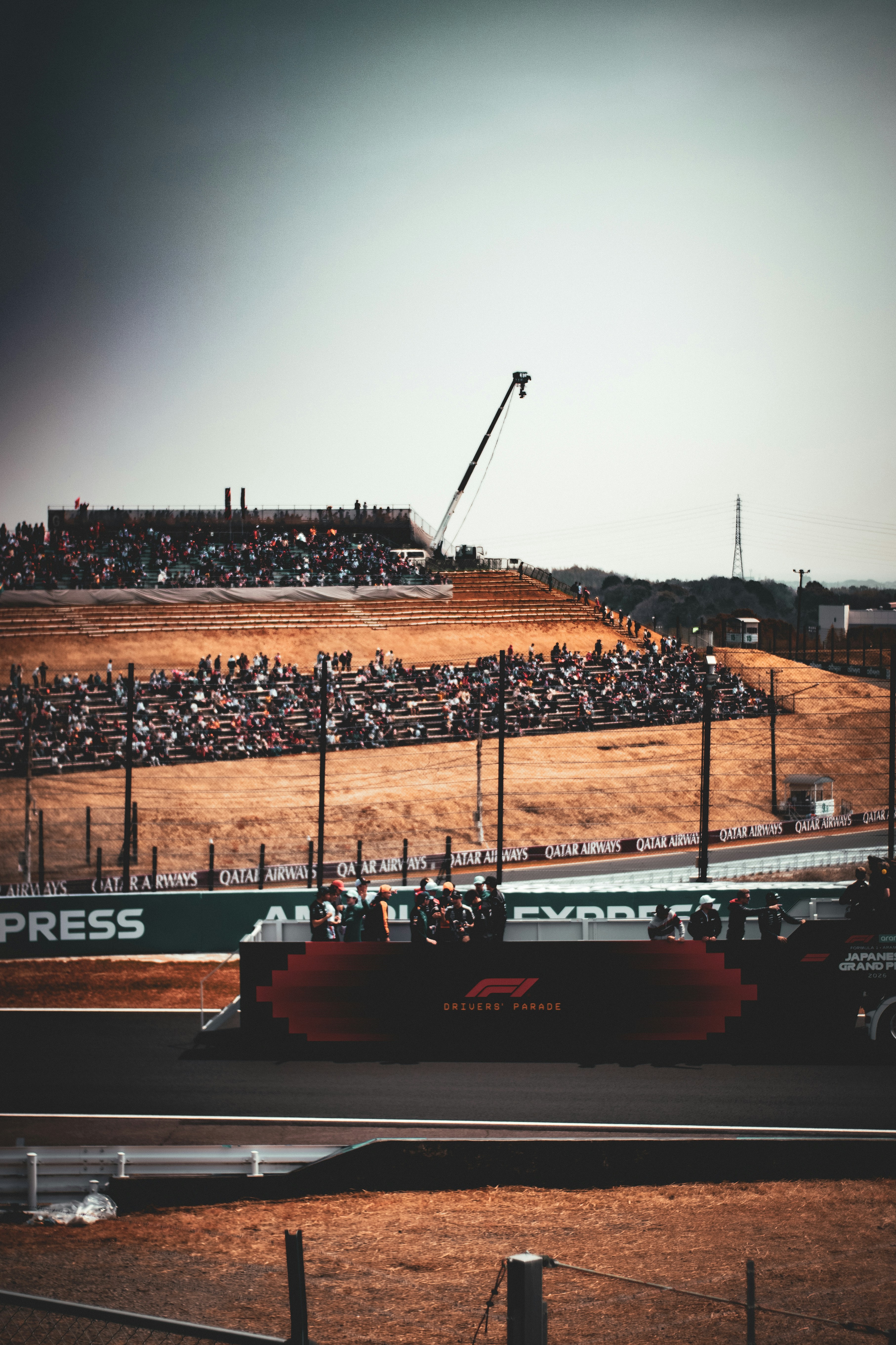 Race track with spectators in grandstands and a crane.