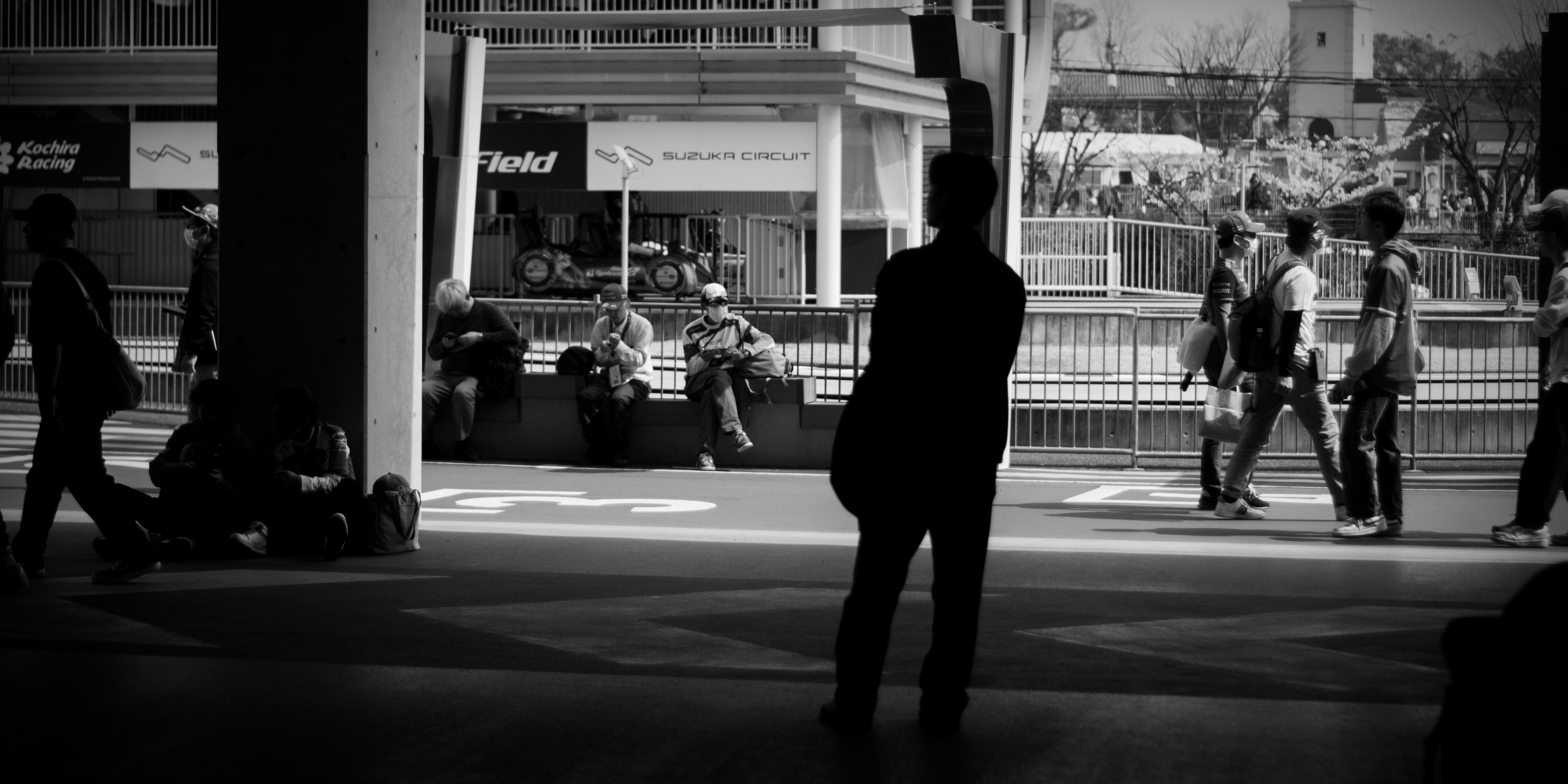 People walking and sitting at a busy urban station.