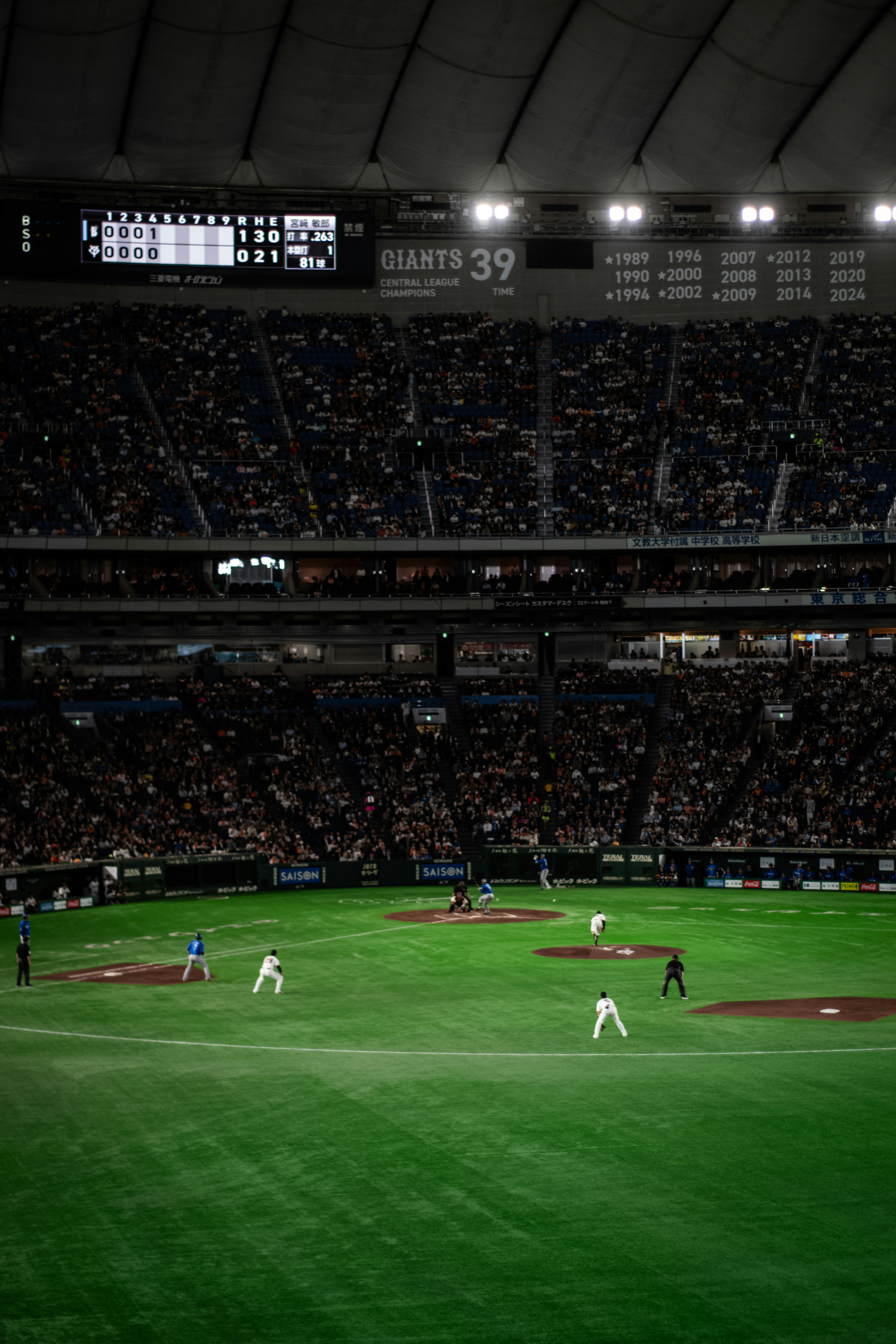 Baseball game in a crowded stadium at night.