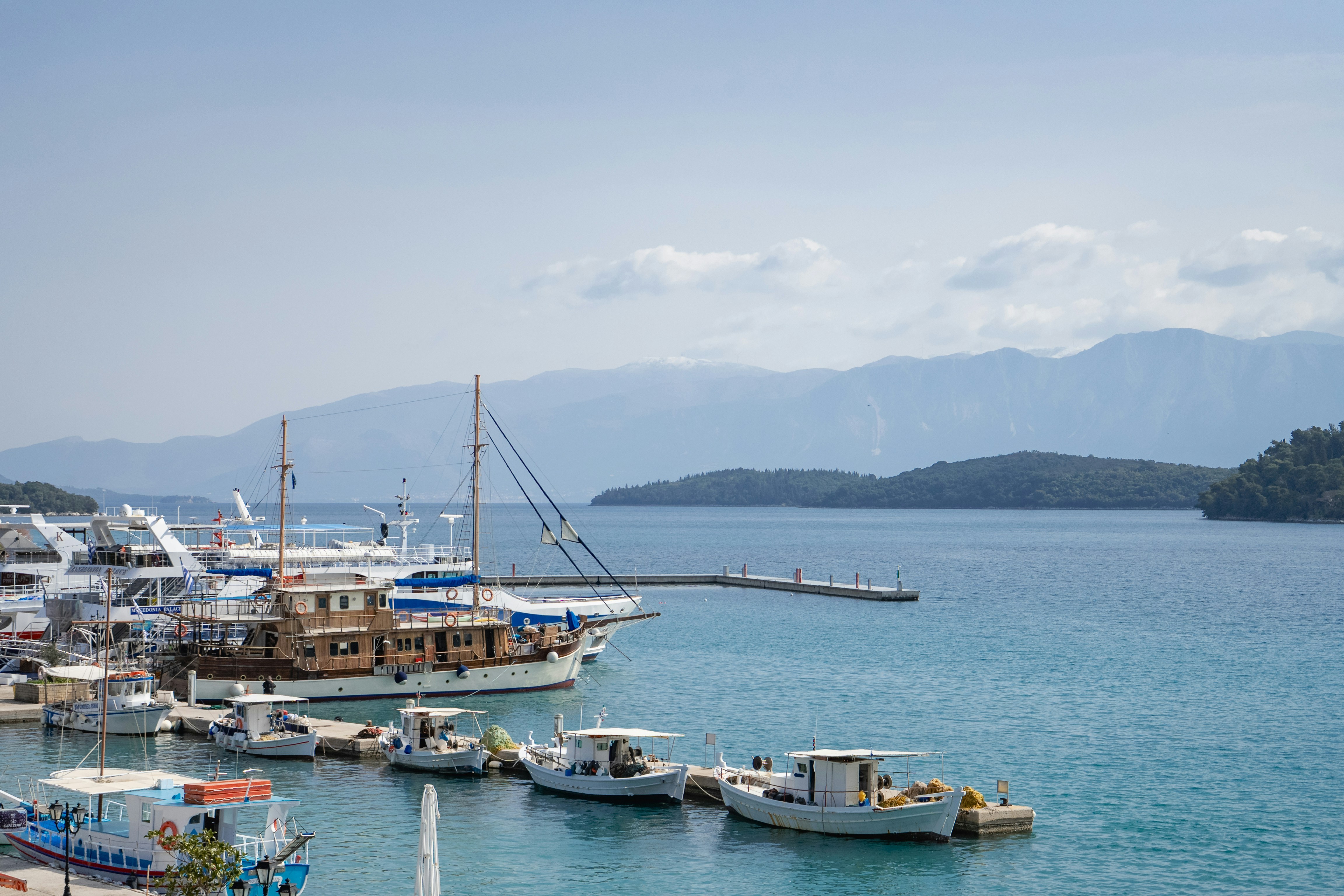 Des bateaux accostés dans un port calme avec des montagnes lointaines.