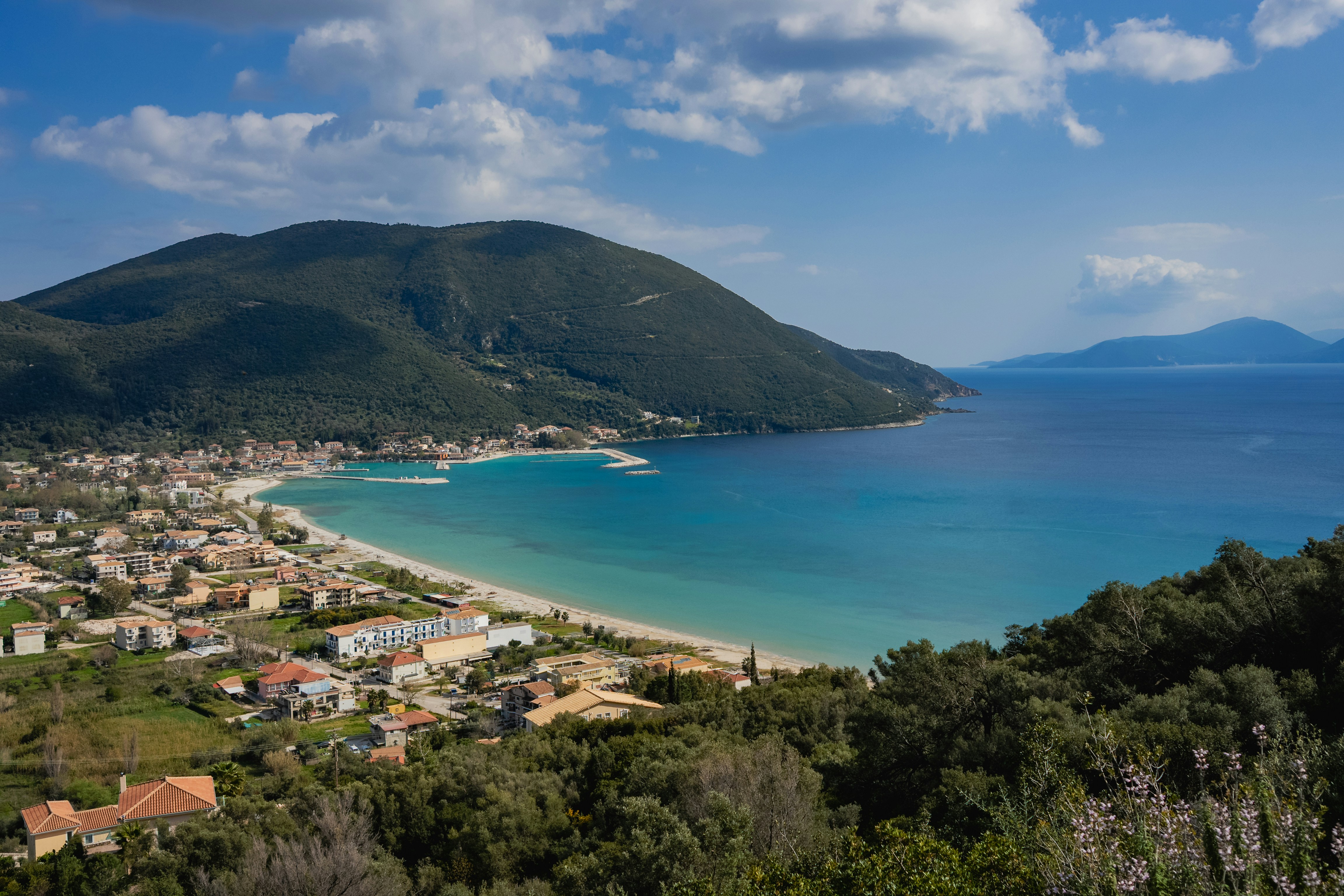 Ville côtière nichée au bord d’une baie turquoise et de collines verdoyantes.