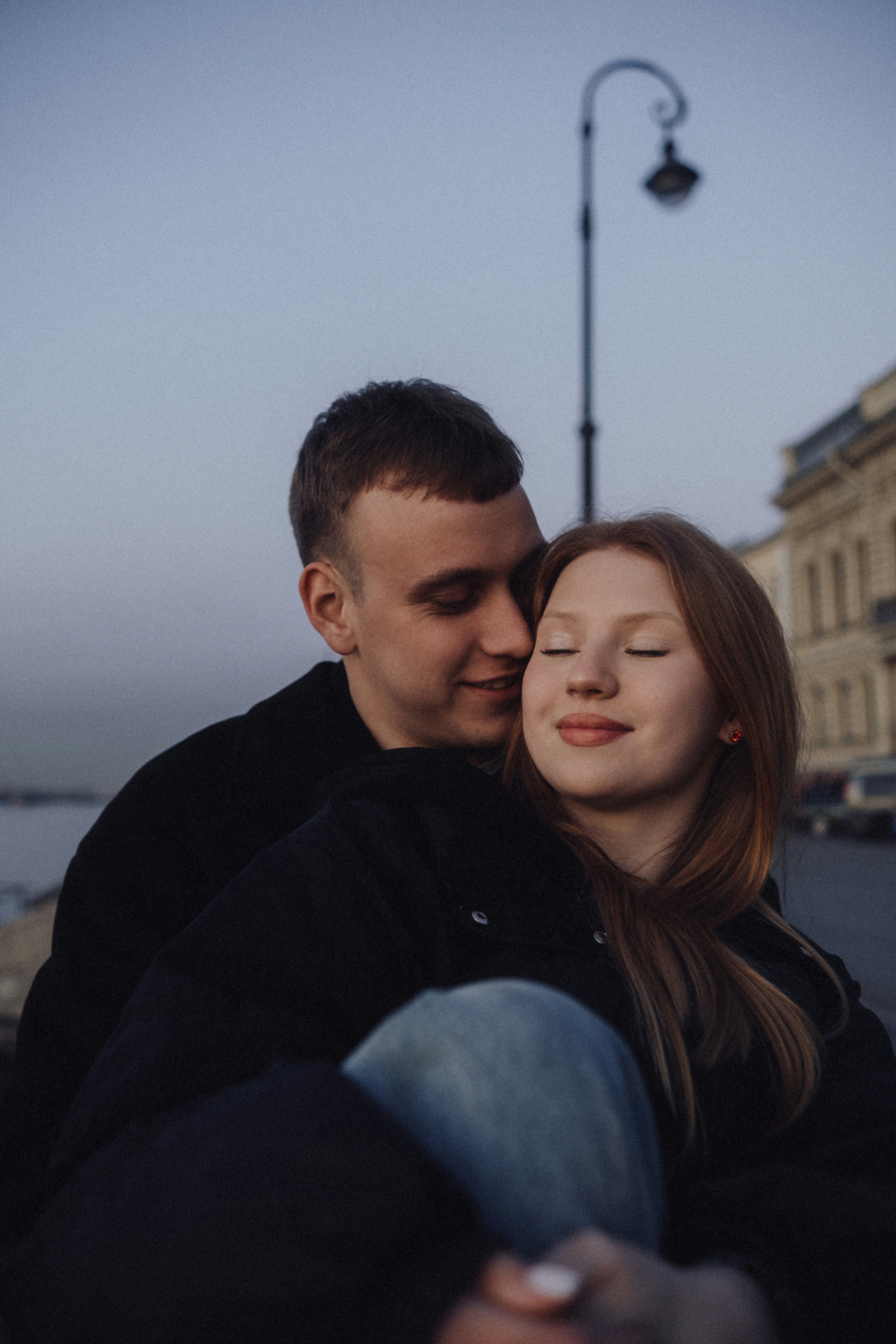 Pareja joven abrazándose al aire libre al anochecer