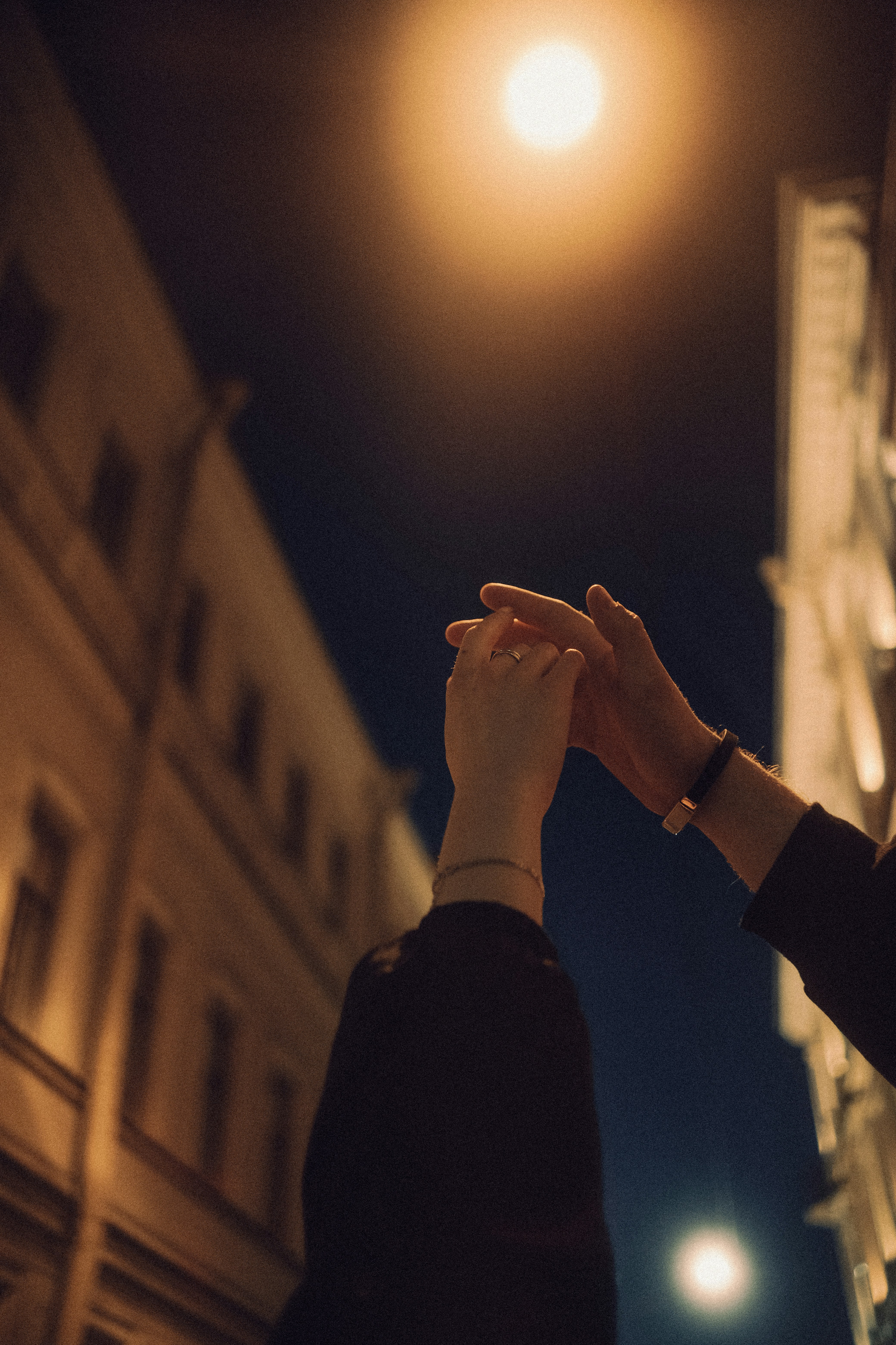 two hands outstretched, reaching for one another on a city street at night