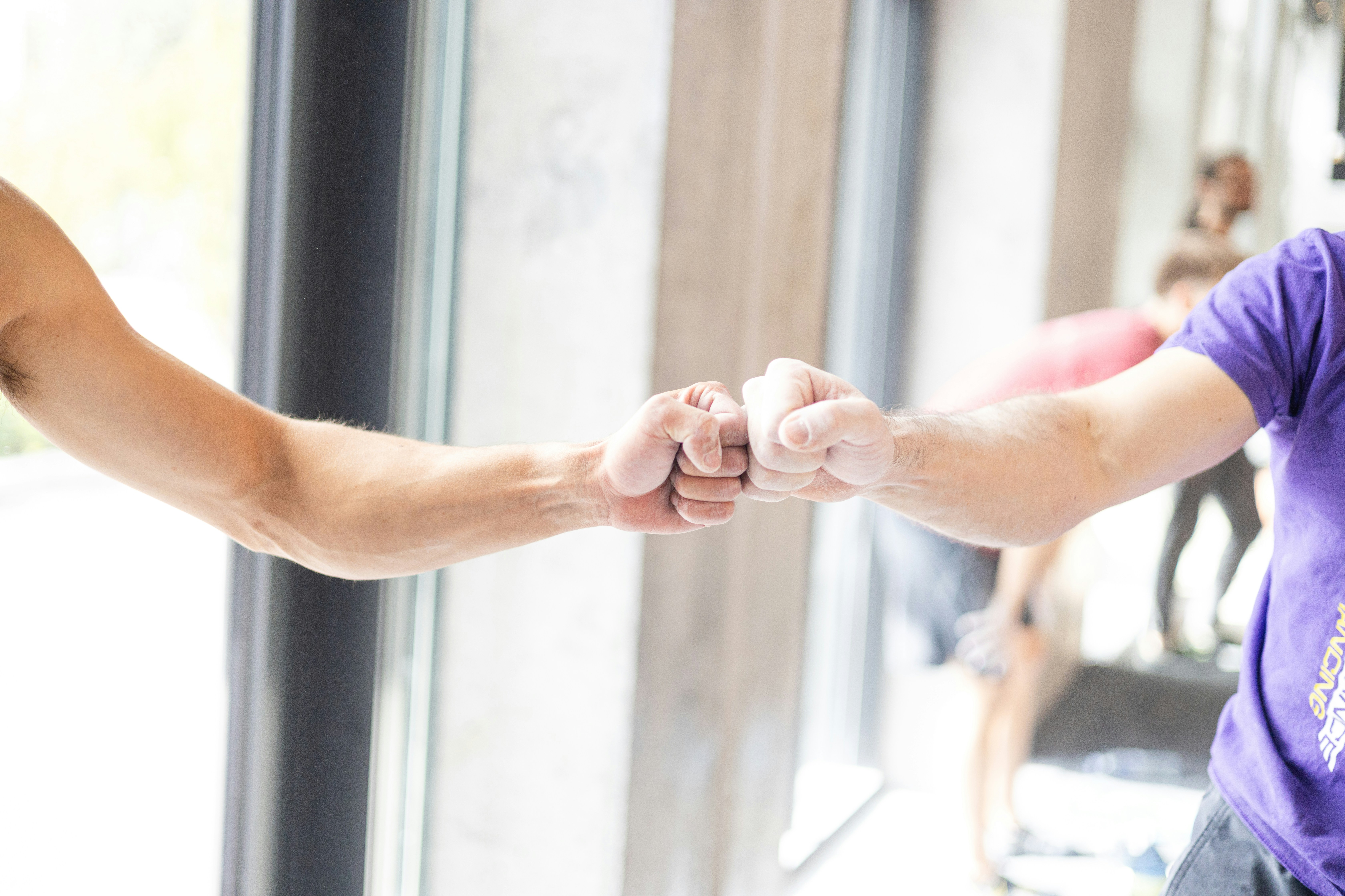 Two people fist bumping in a gym.