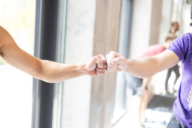 Two people fist bumping in a gym.