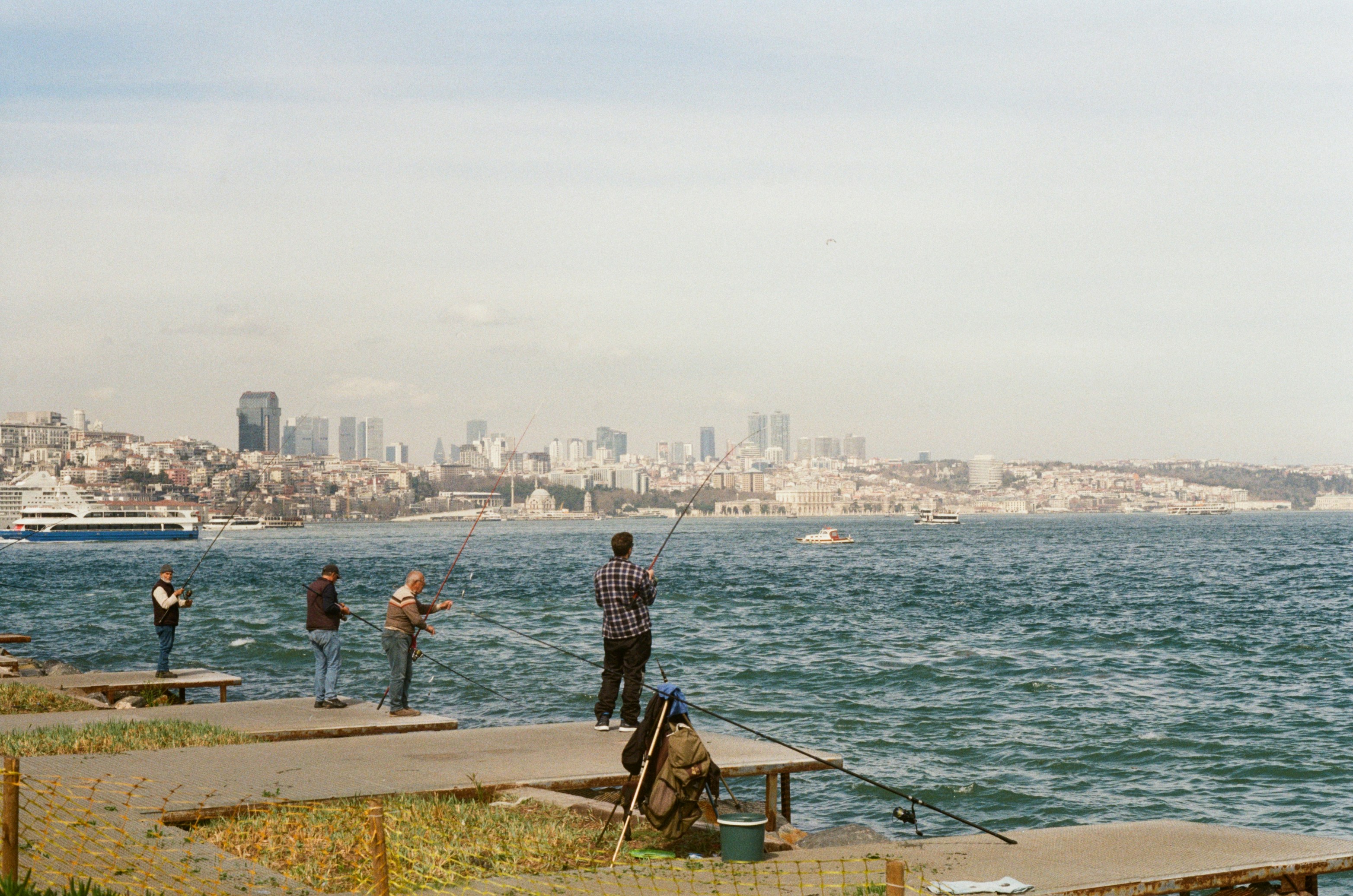 People fishing by the water with city skyline