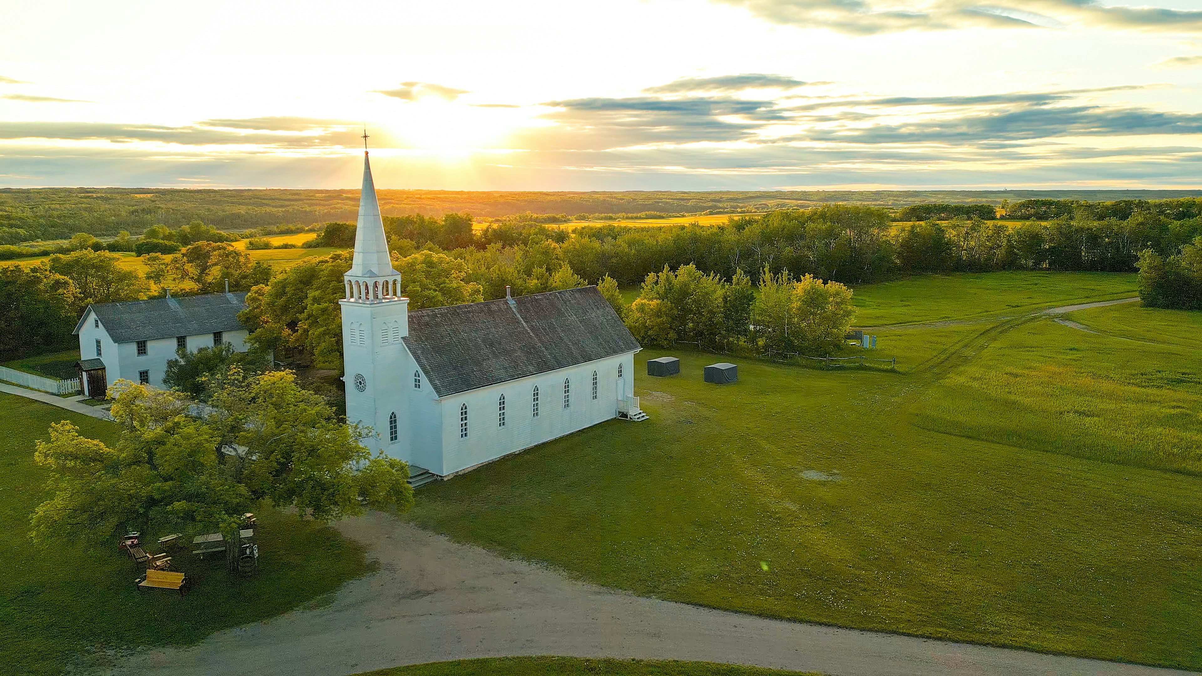 Weiße Kirche mit Turm bei Sonnenuntergang in ländlicher Landschaft