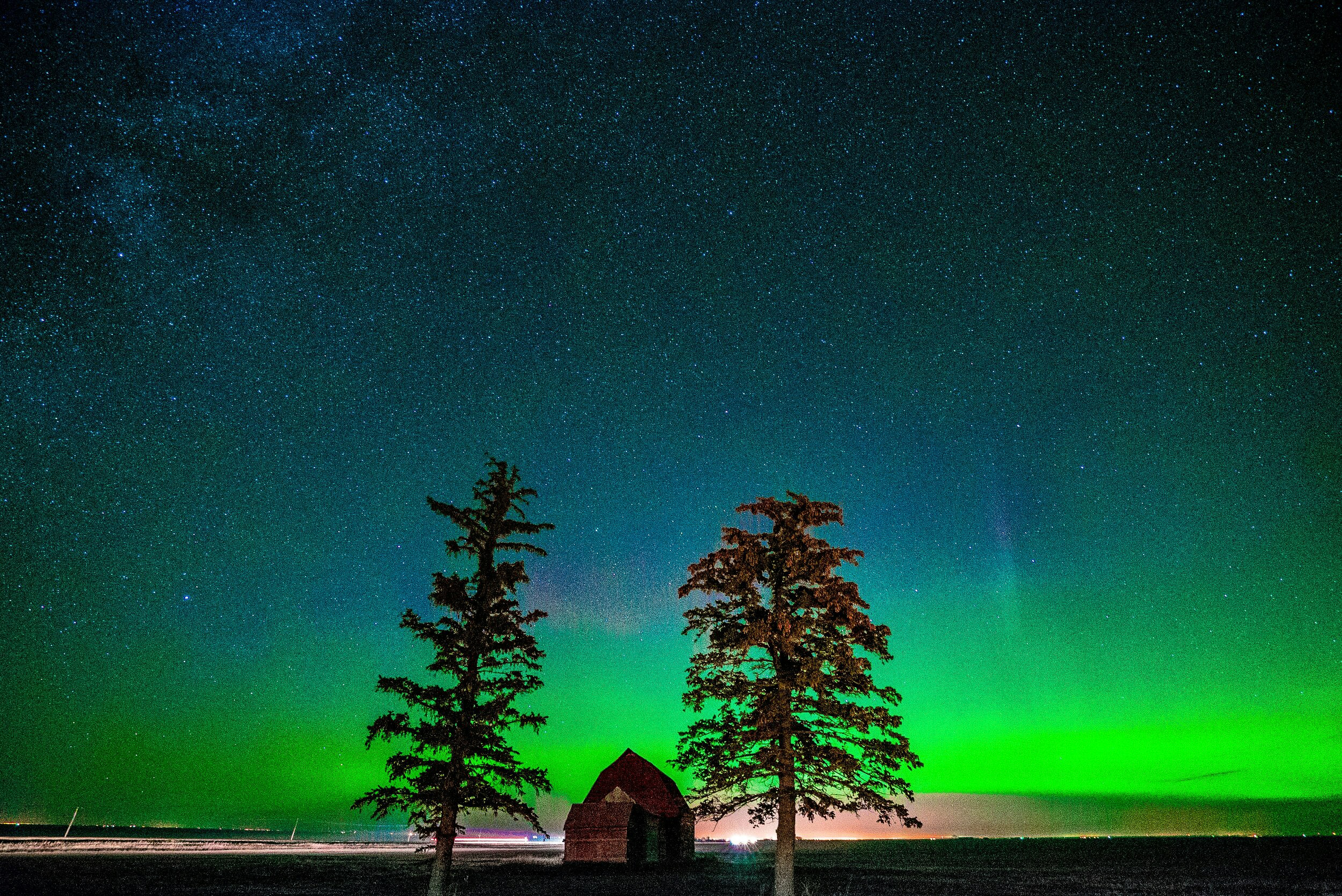 Aurora borealis über einem kleinen Gebäude und Bäumen
