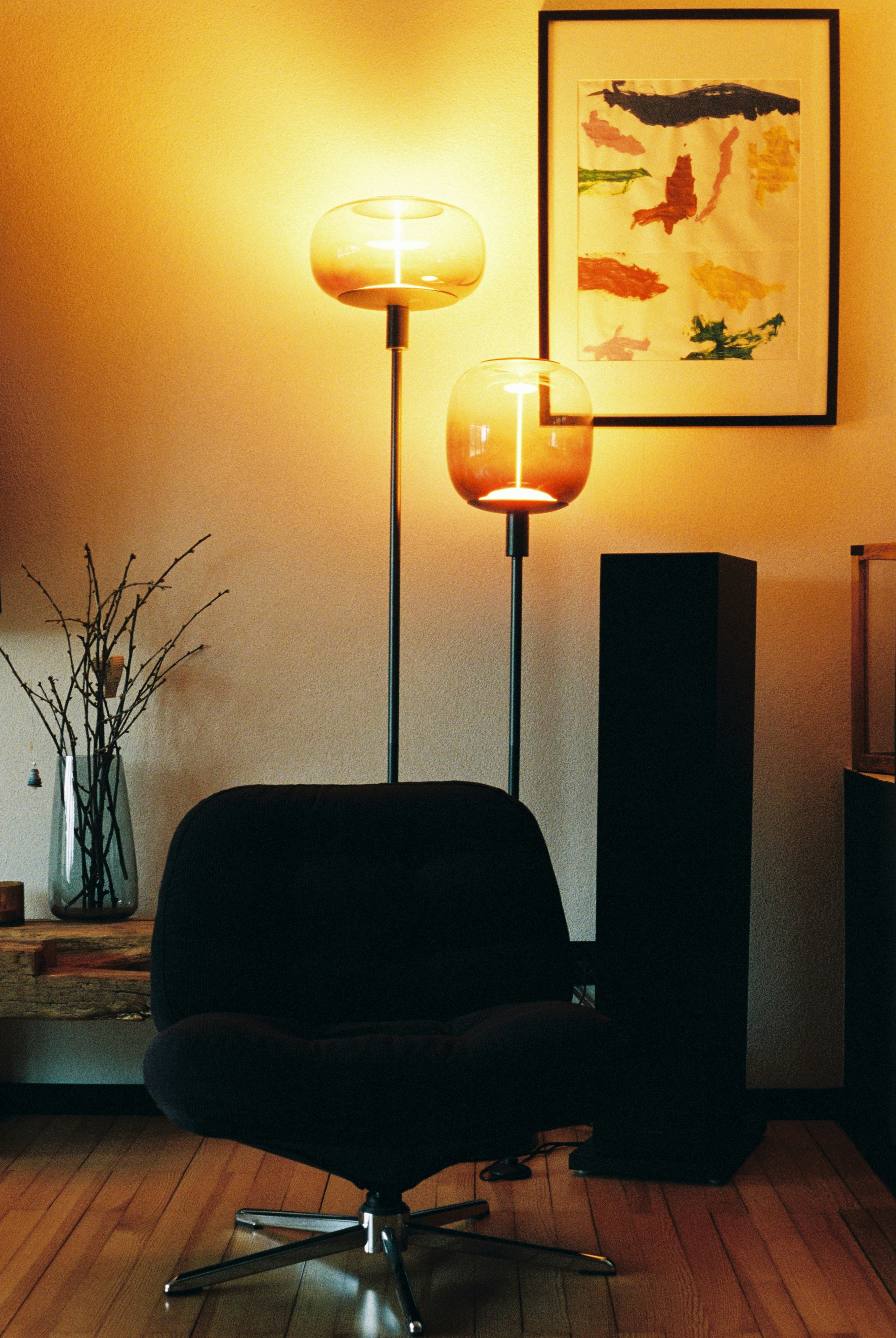 Two modern lamps illuminate a dark armchair.