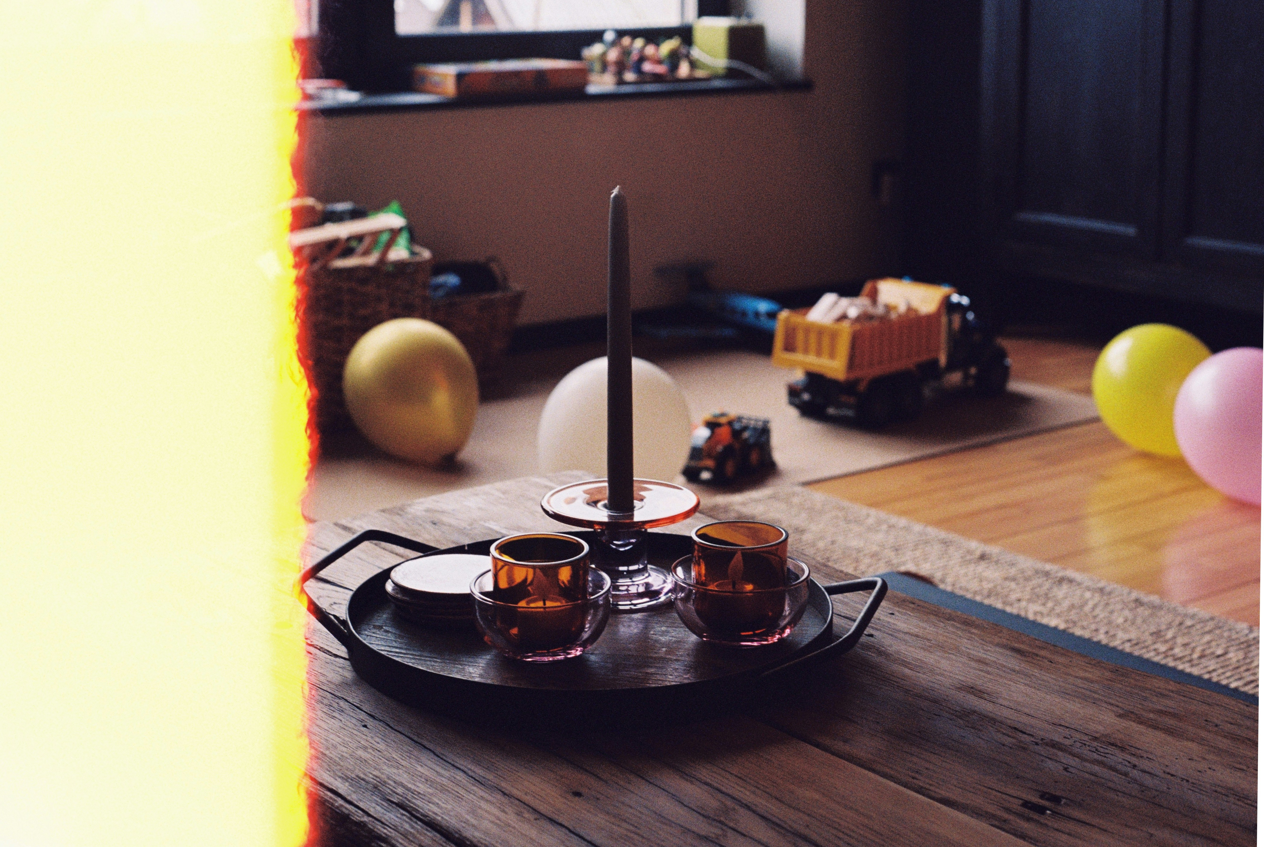 Two small glasses on a tray with toys in background