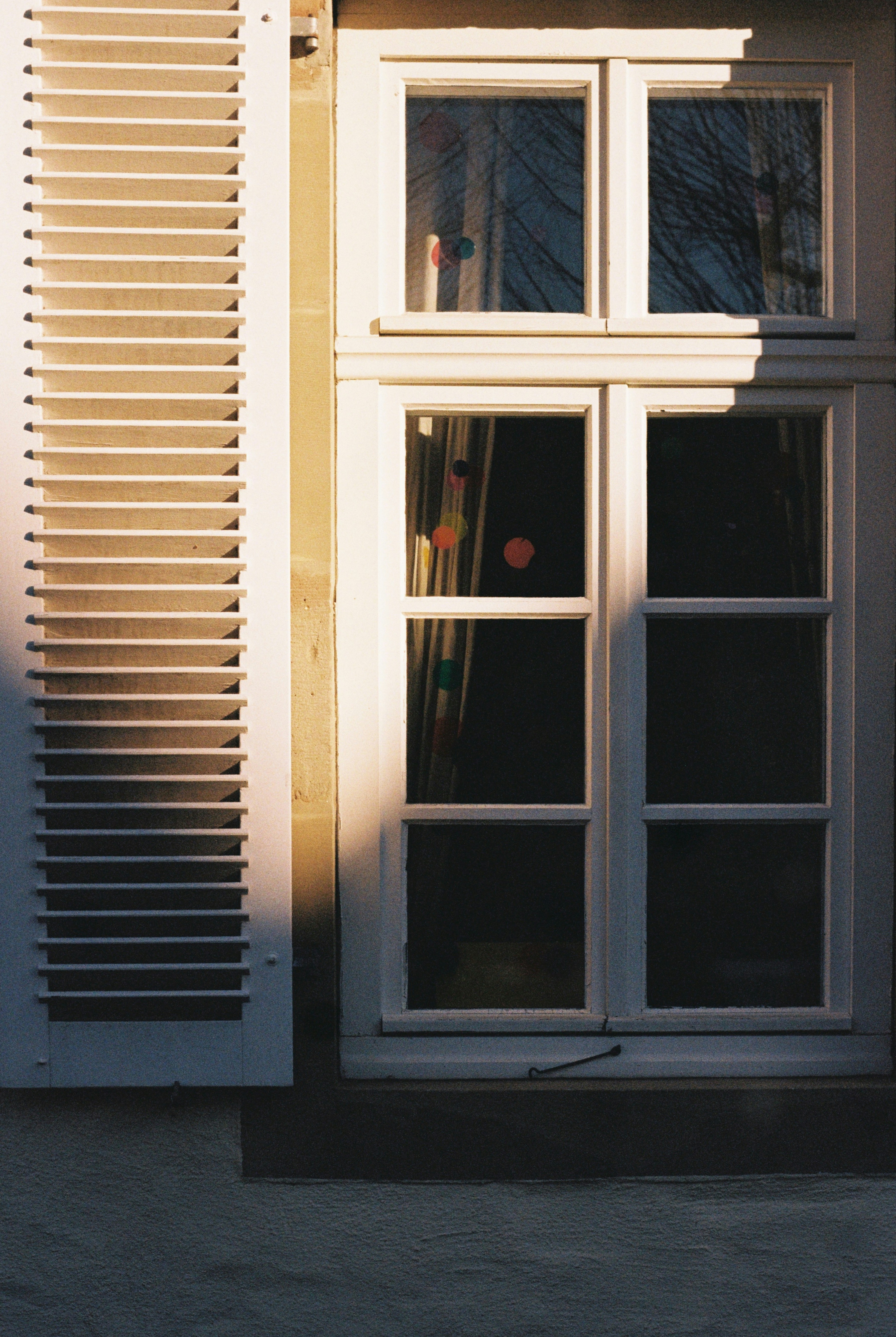 White window with open shutters and sunlight