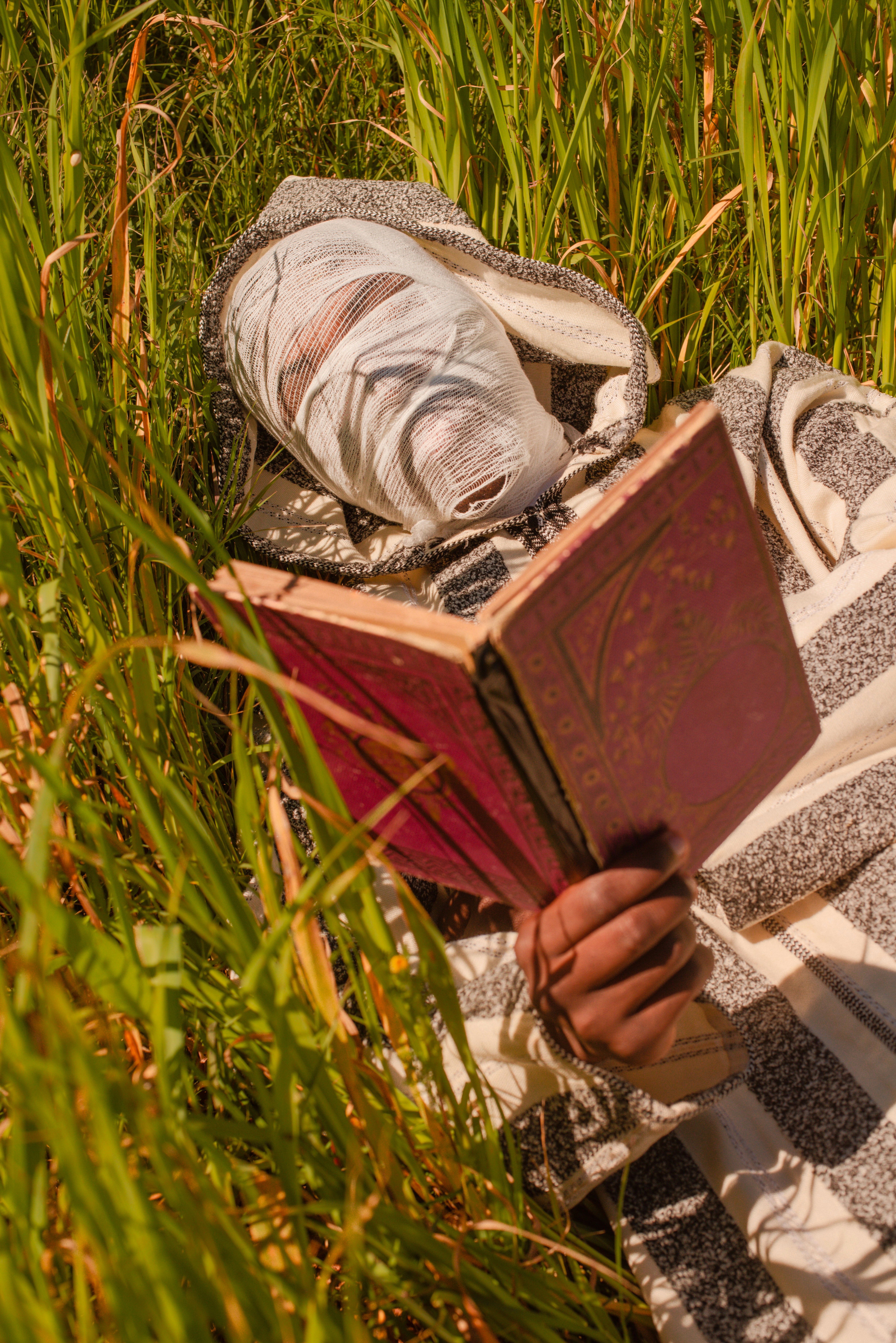 Person lying in grass reading an old book
