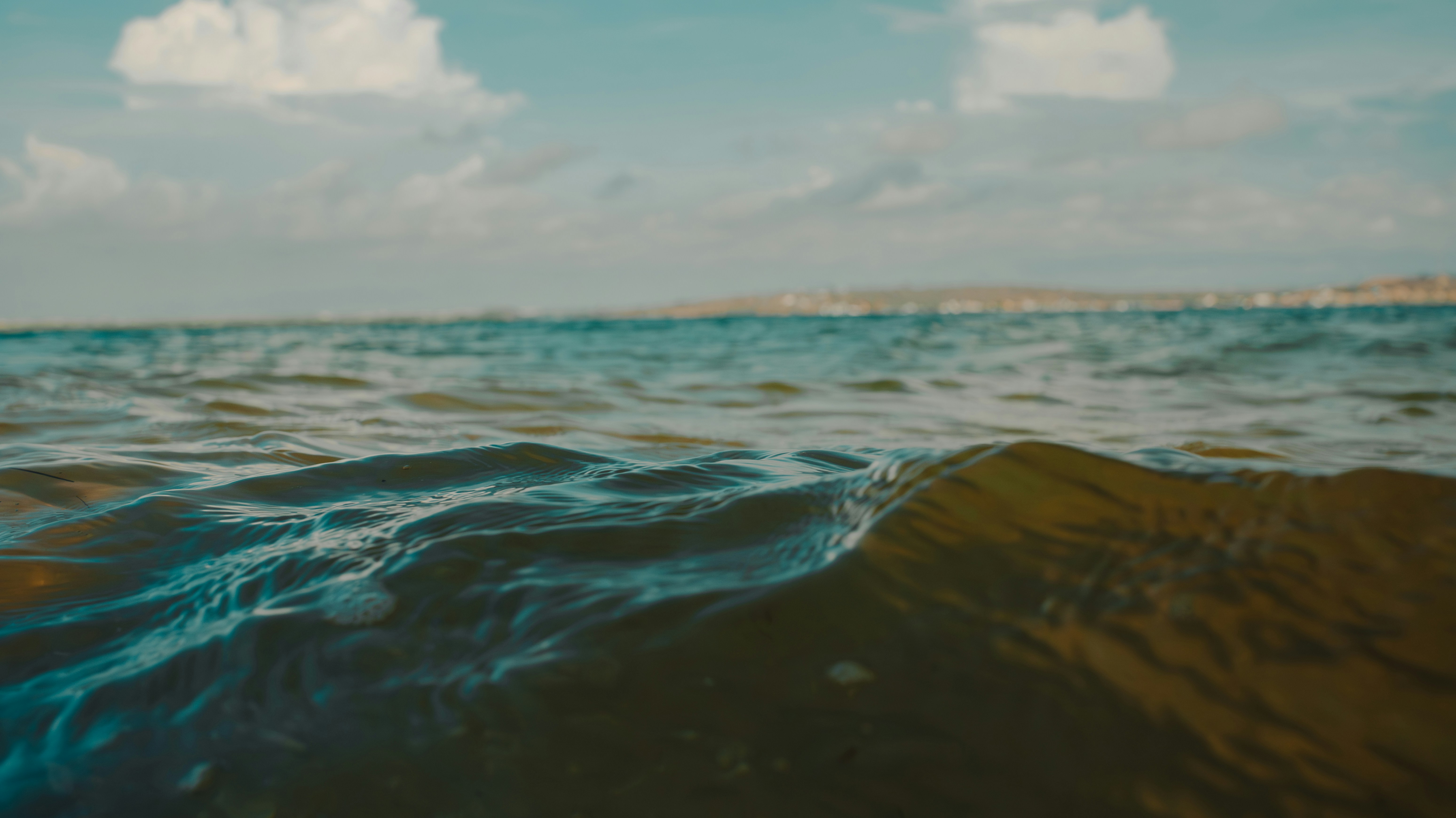 Gentle waves on a clear day with distant coastline.