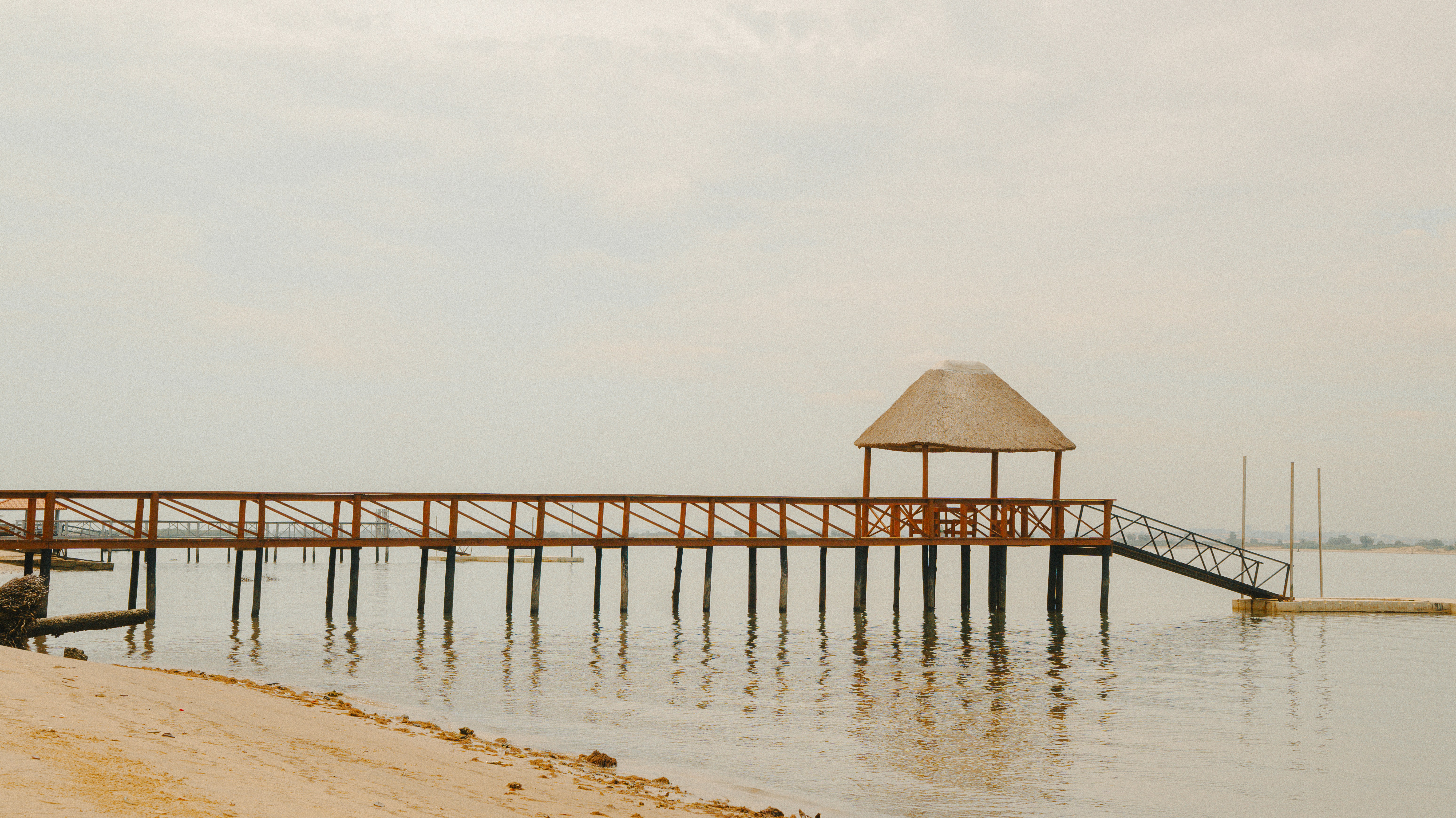 Wooden pier with thatched roof shelter over calm water
