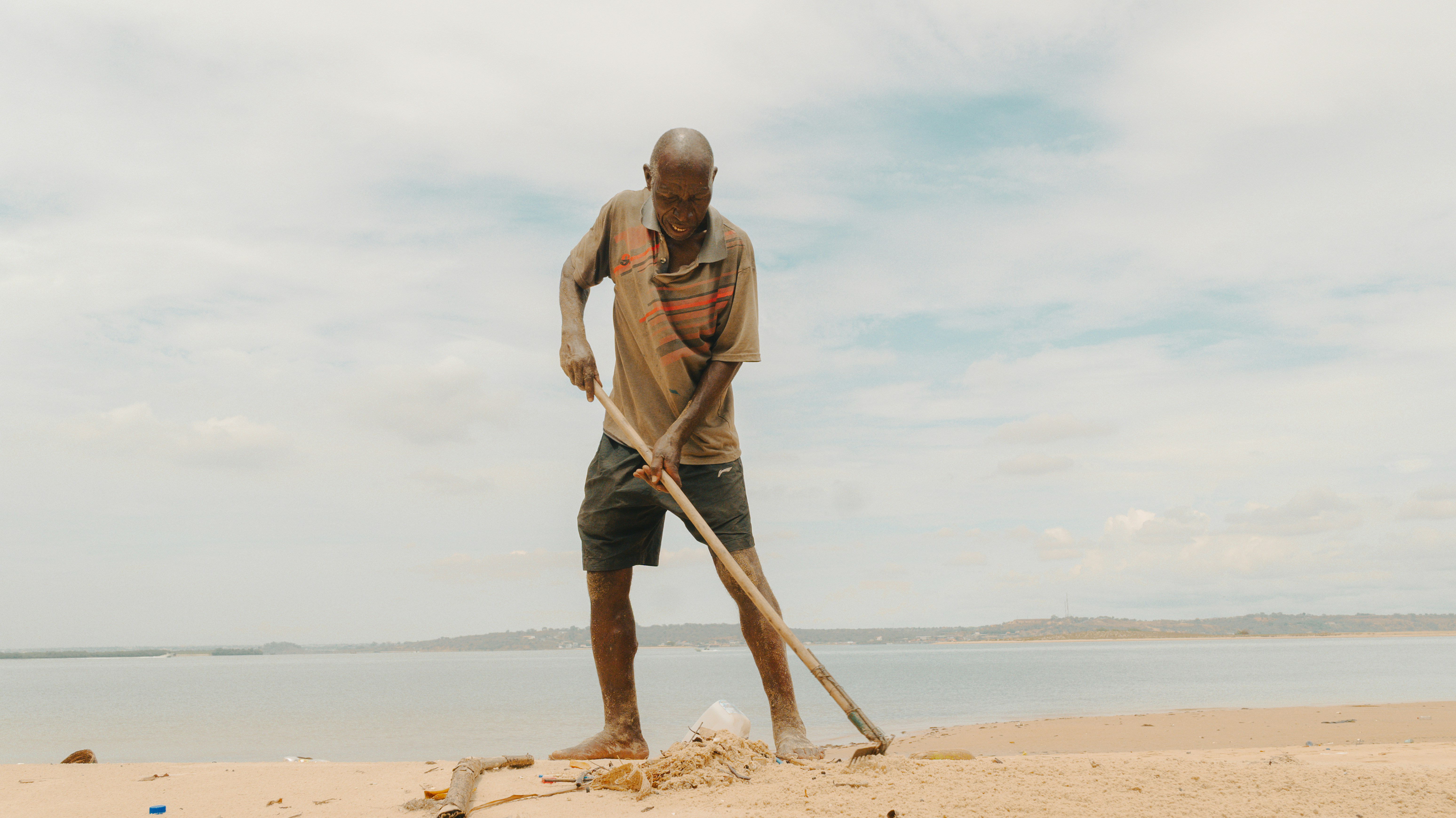 Man with hoe working on a sandy beach