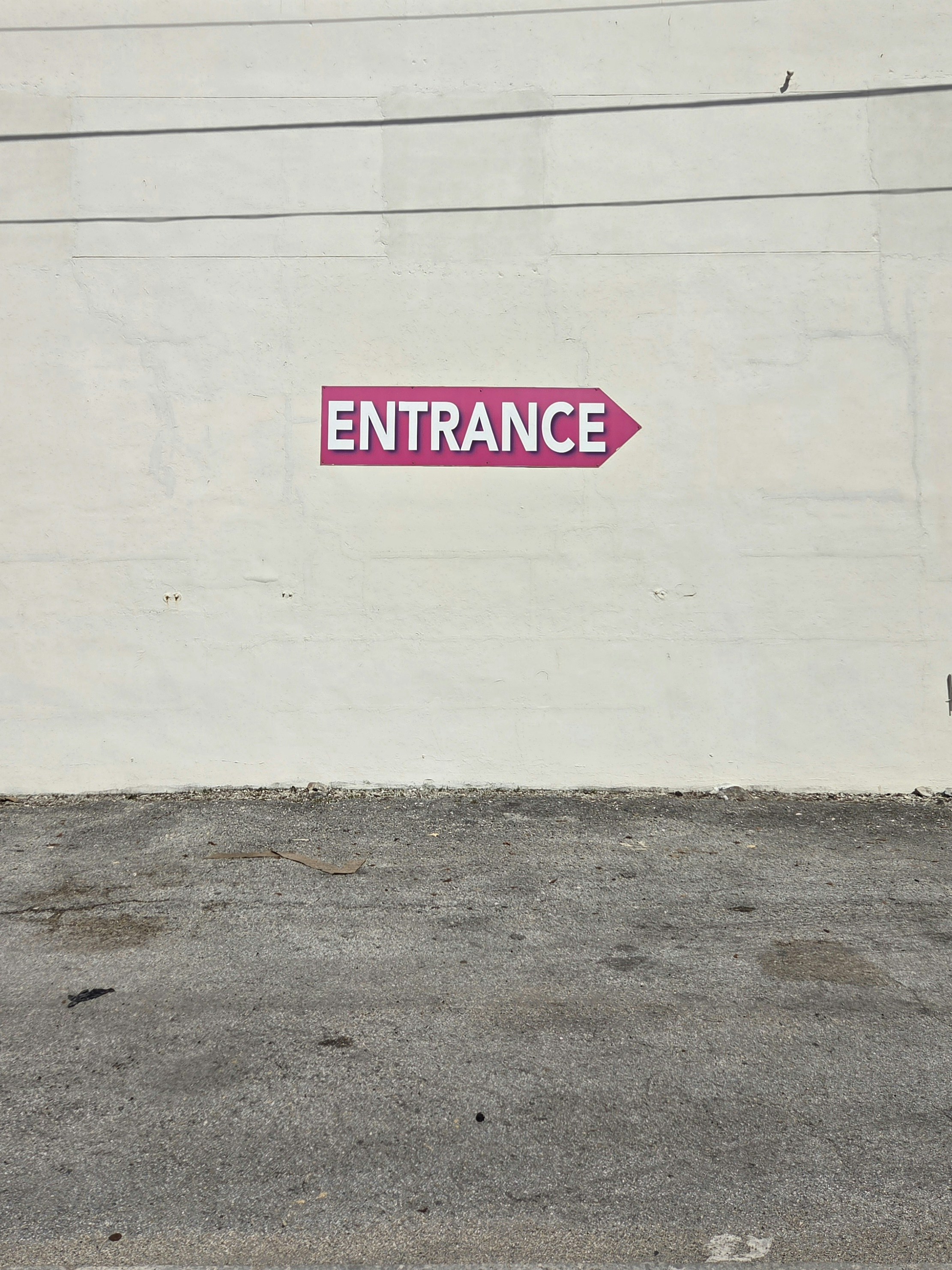Placa de entrada rosa em uma parede branca
