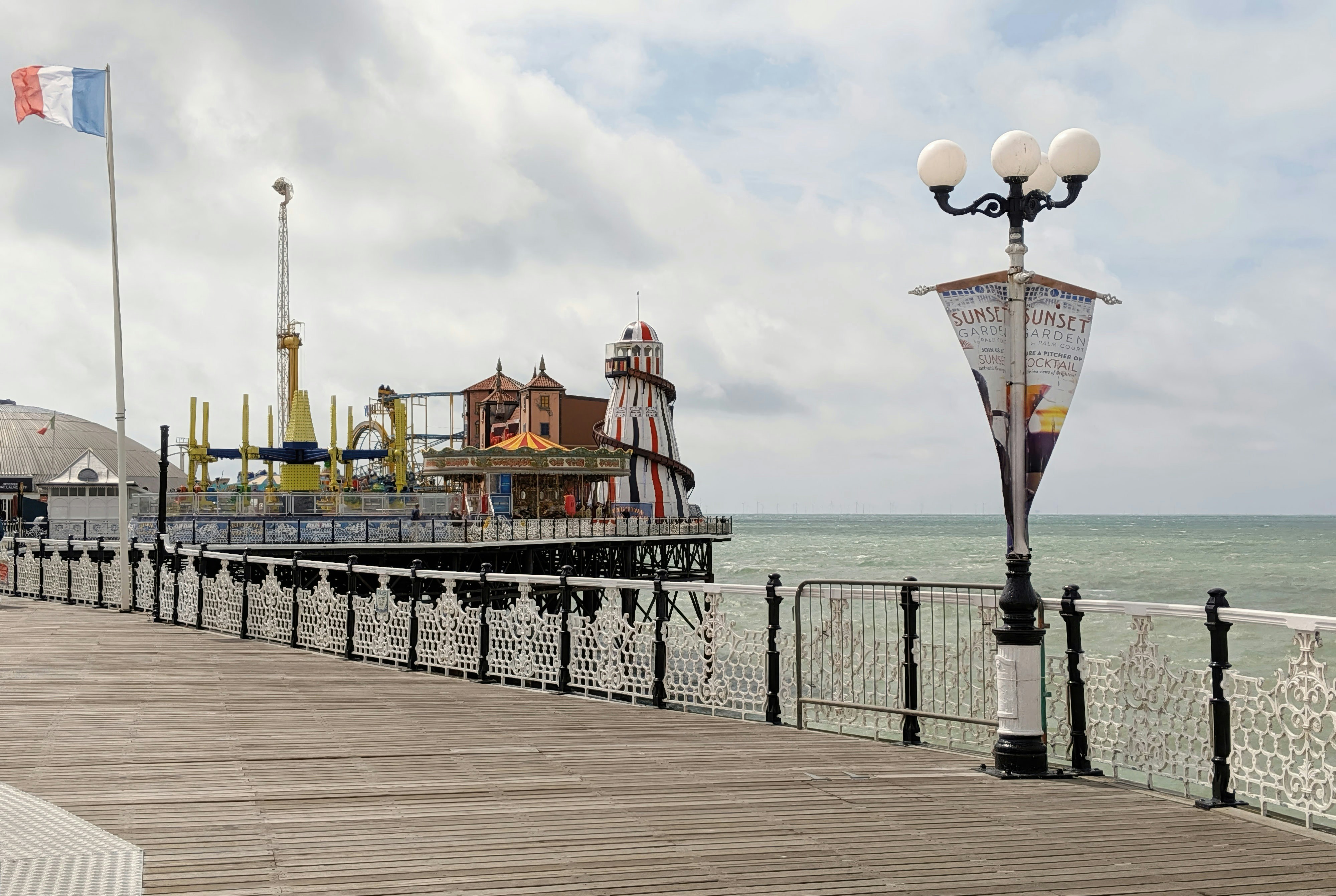 Ein Pier mit Fahrgeschäften und einer französischen Flagge.