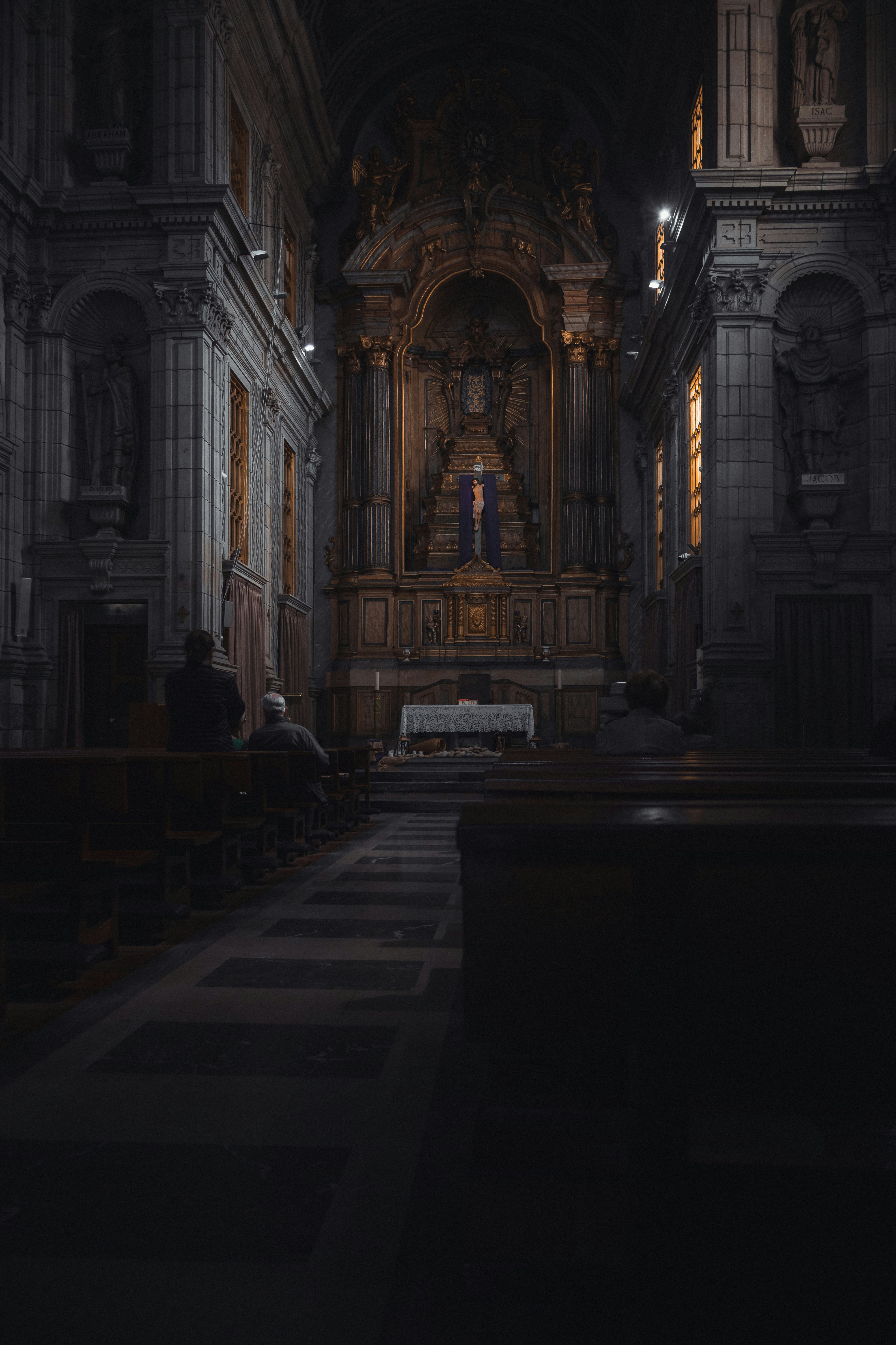 Dimly lit church interior with people seated in pews.
