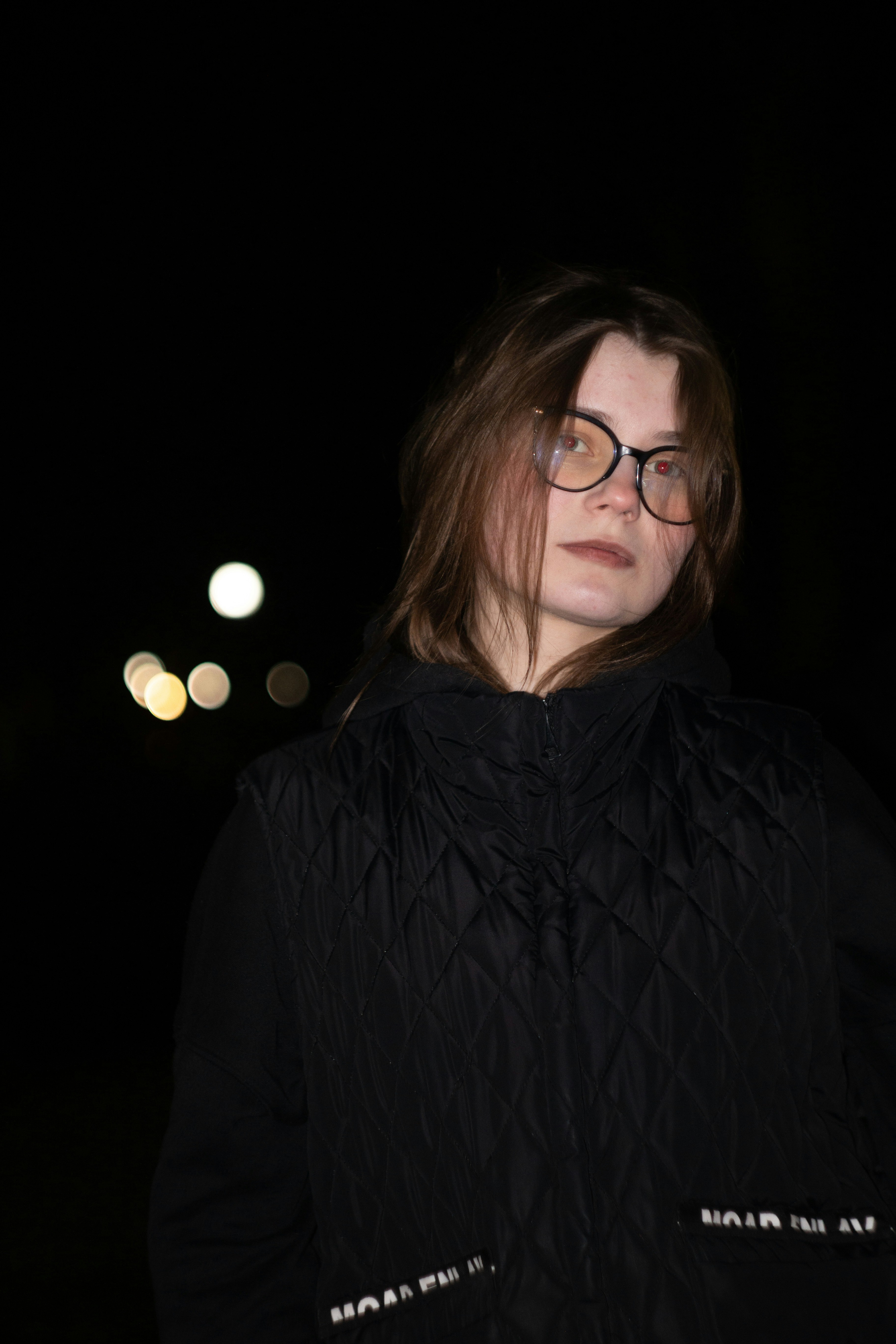 Junge Frau mit Brille nachts und Bokeh-Lichtern