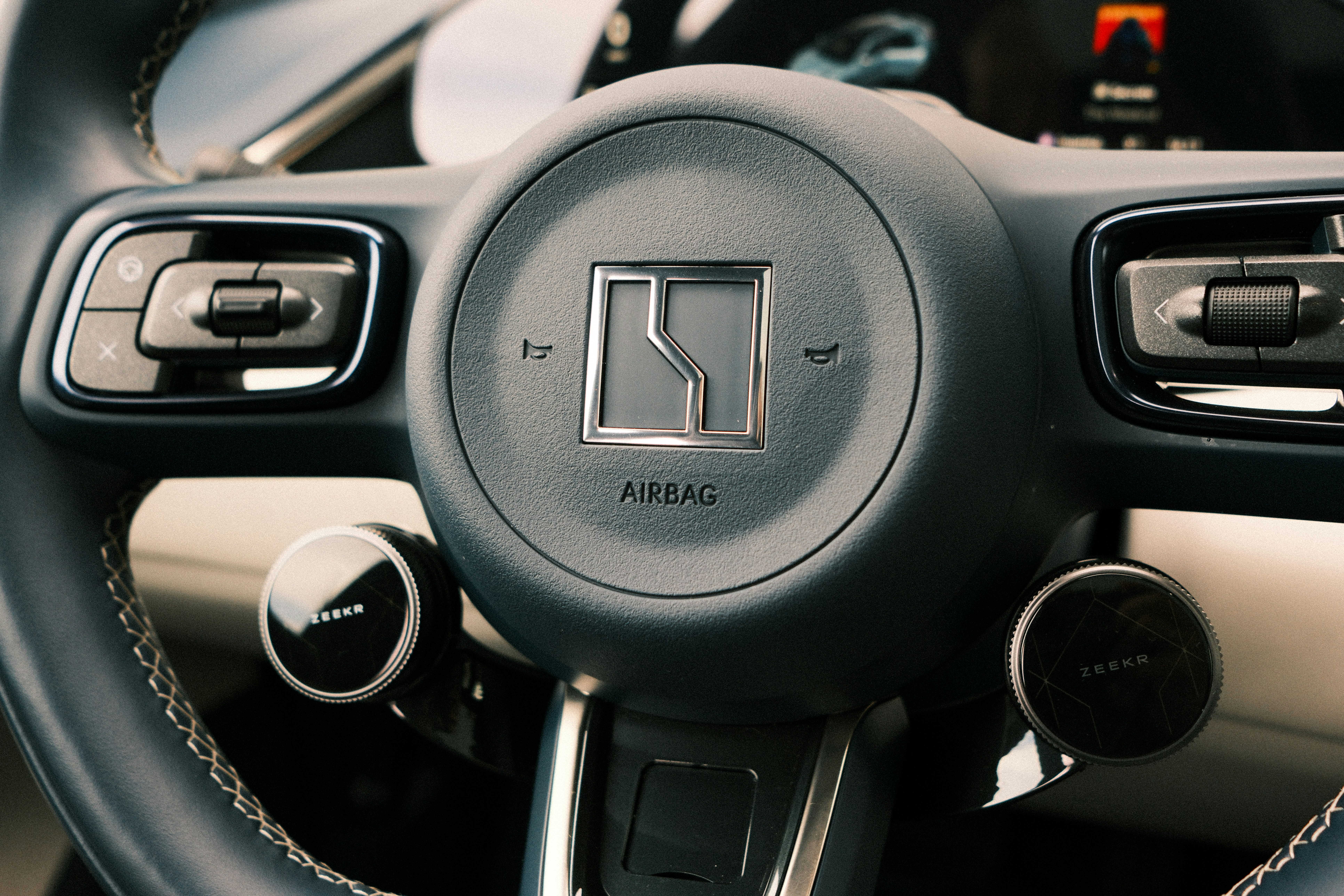 Close-up of a car's steering wheel with logo.