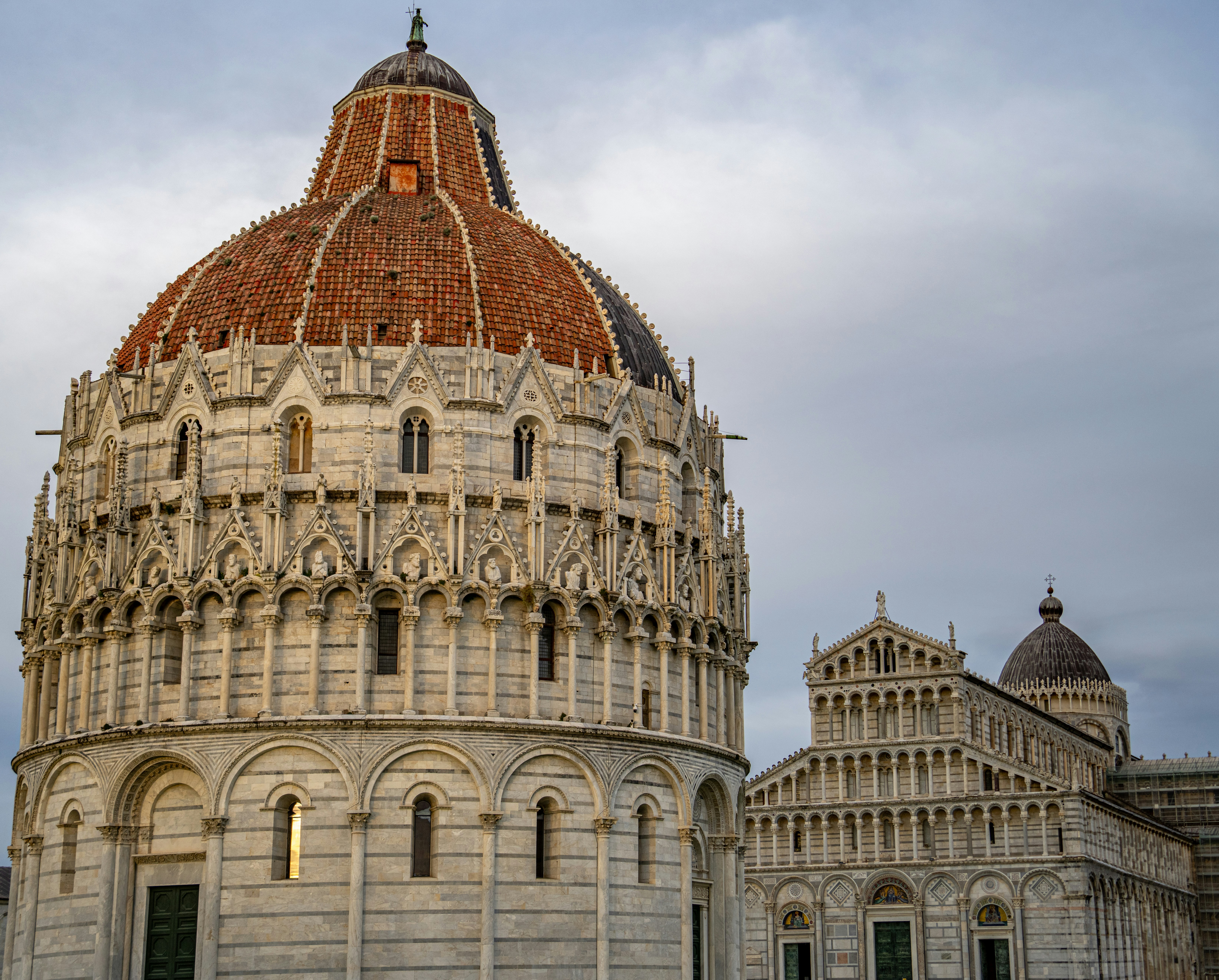 Ornate baptistery and cathedral against cloudy sky